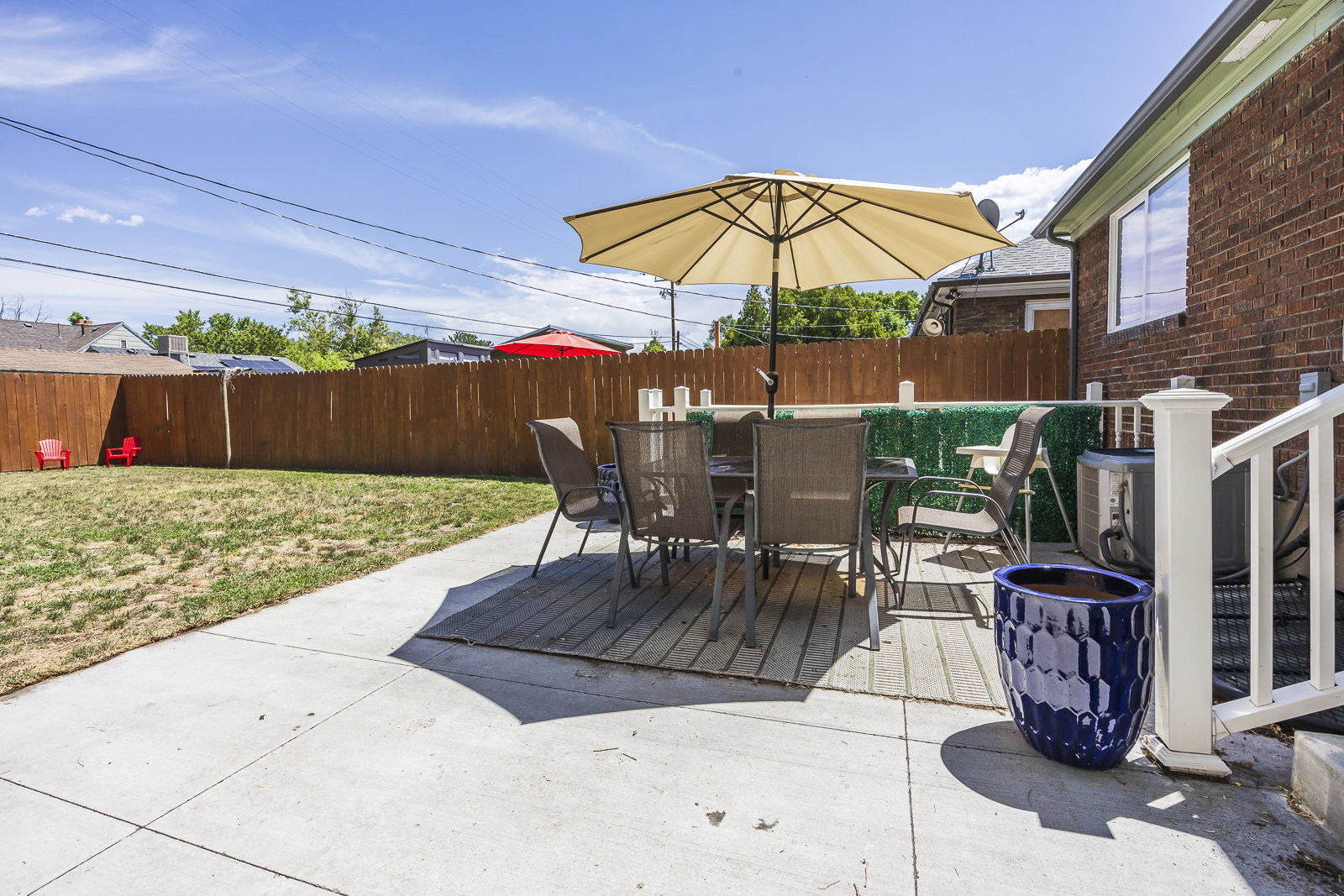 Expansive backyard featuring a concrete patio, wooden privacy fence, and a brick exterior