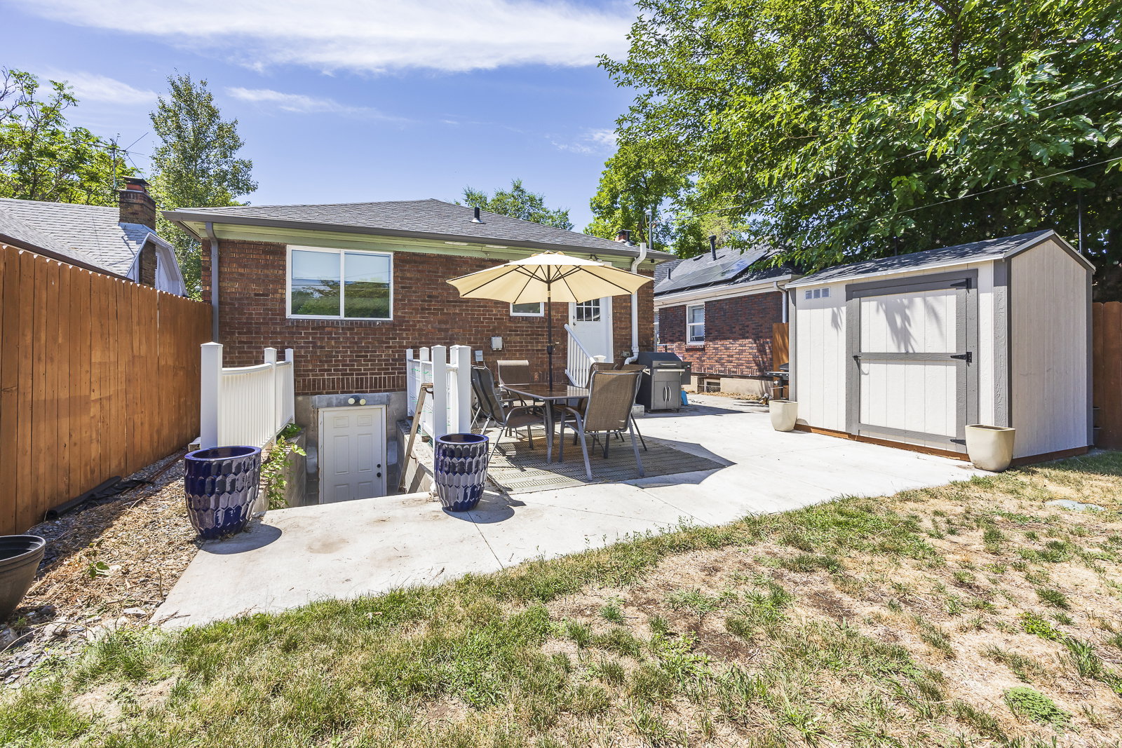 Expansive concrete patio area featuring a dining set and a large storage shed with dual access doors