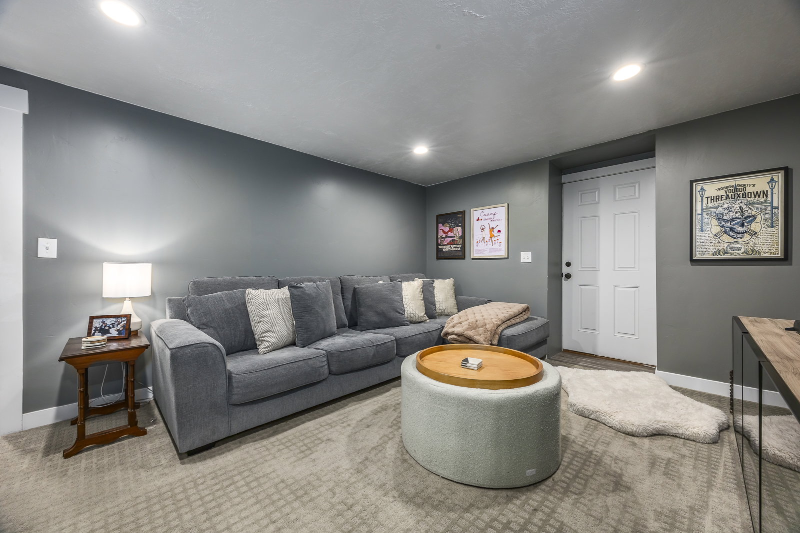 Recessed lighting illuminates a spacious room featuring textured gray carpeting and dark gray walls