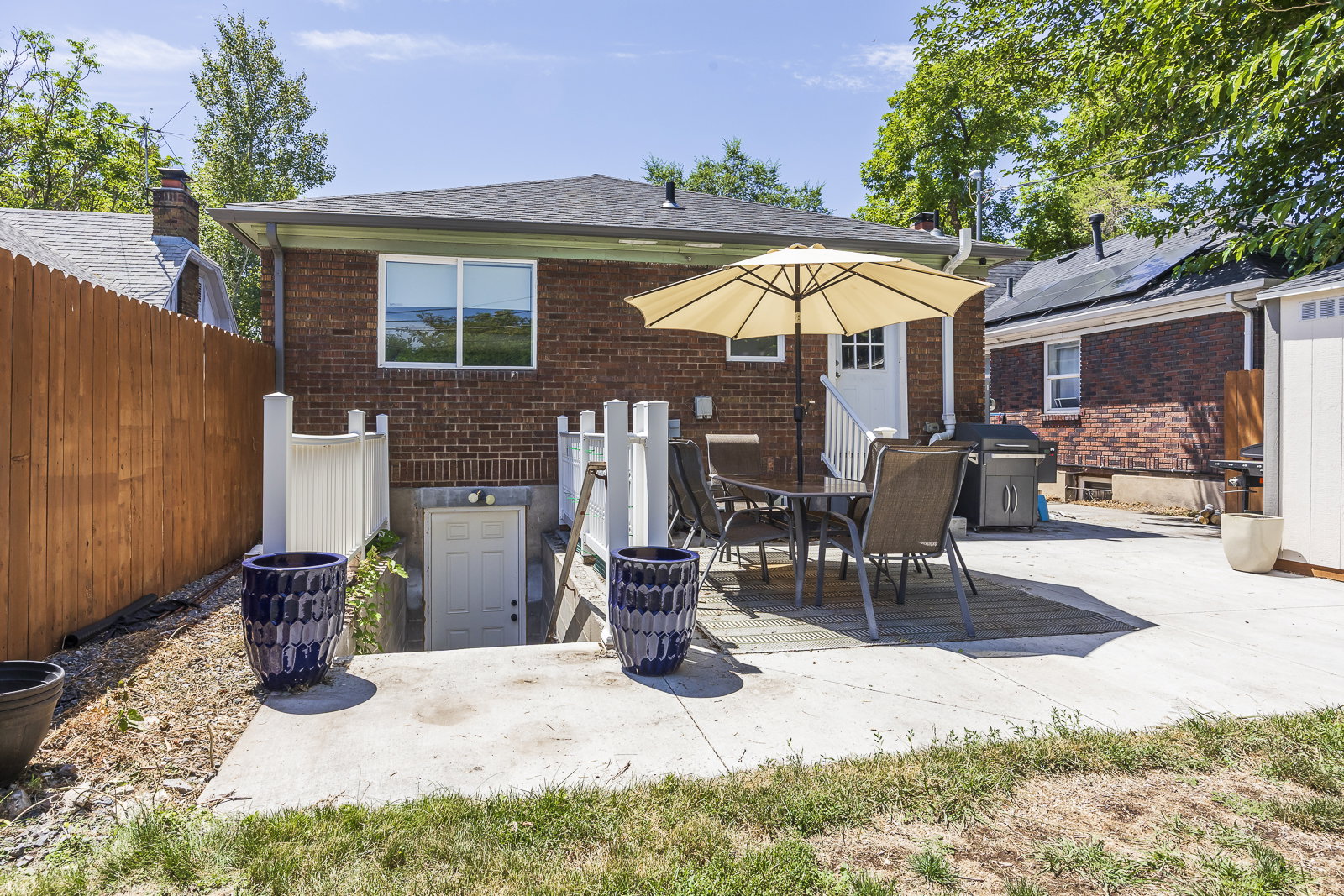 Brick exterior featuring a deck with concrete patio surround, white exterior door, and a lower-level entrance