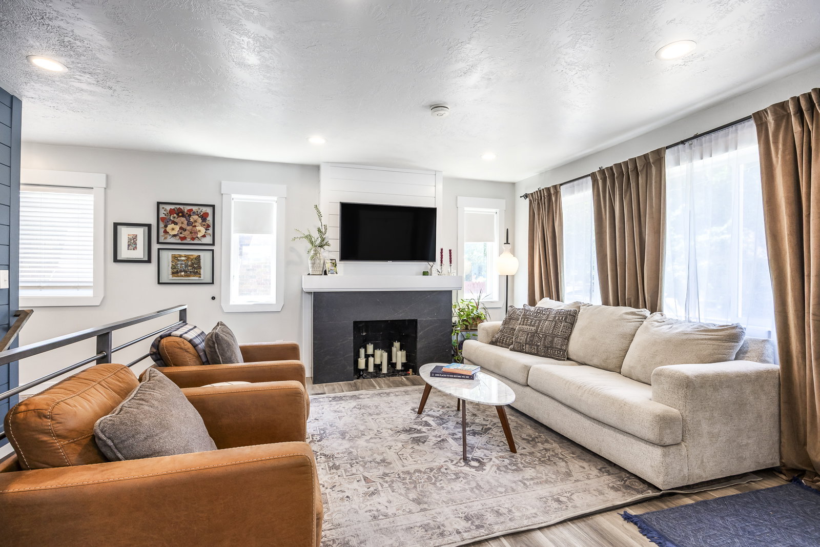 Living area featuring wood-finish flooring, recessed lighting, and a modern fireplace with a dark surround and white mantel