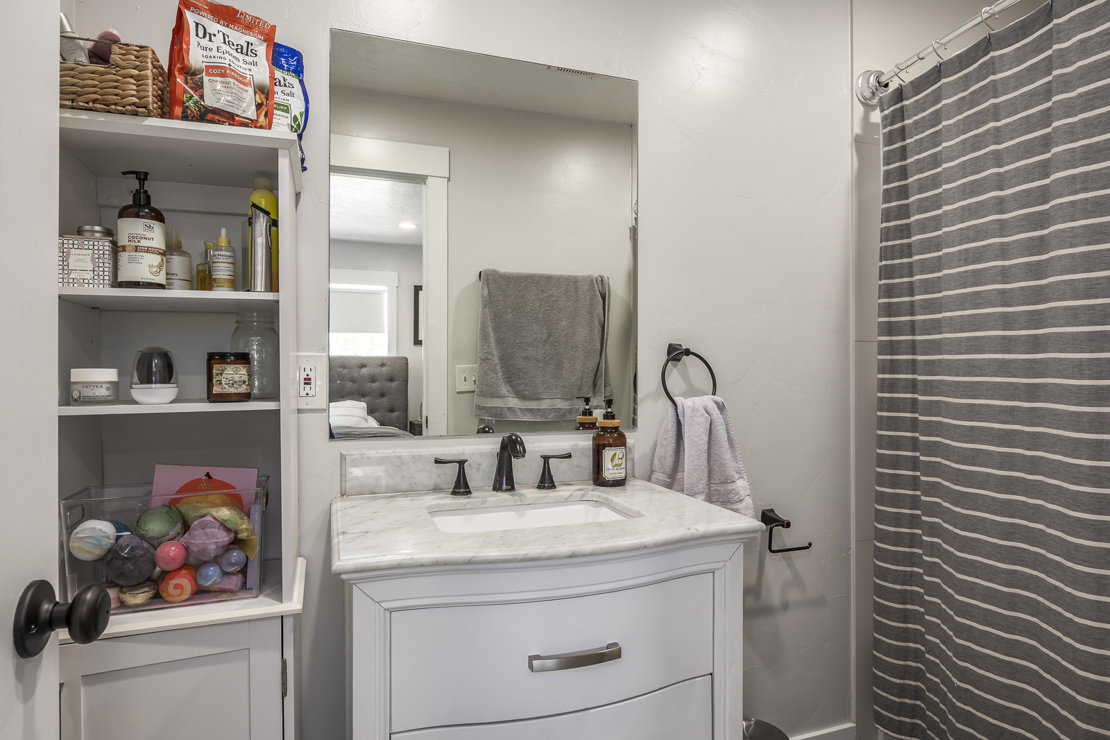 Bathroom vanity with a white cabinet, integrated sink, and stone countertop