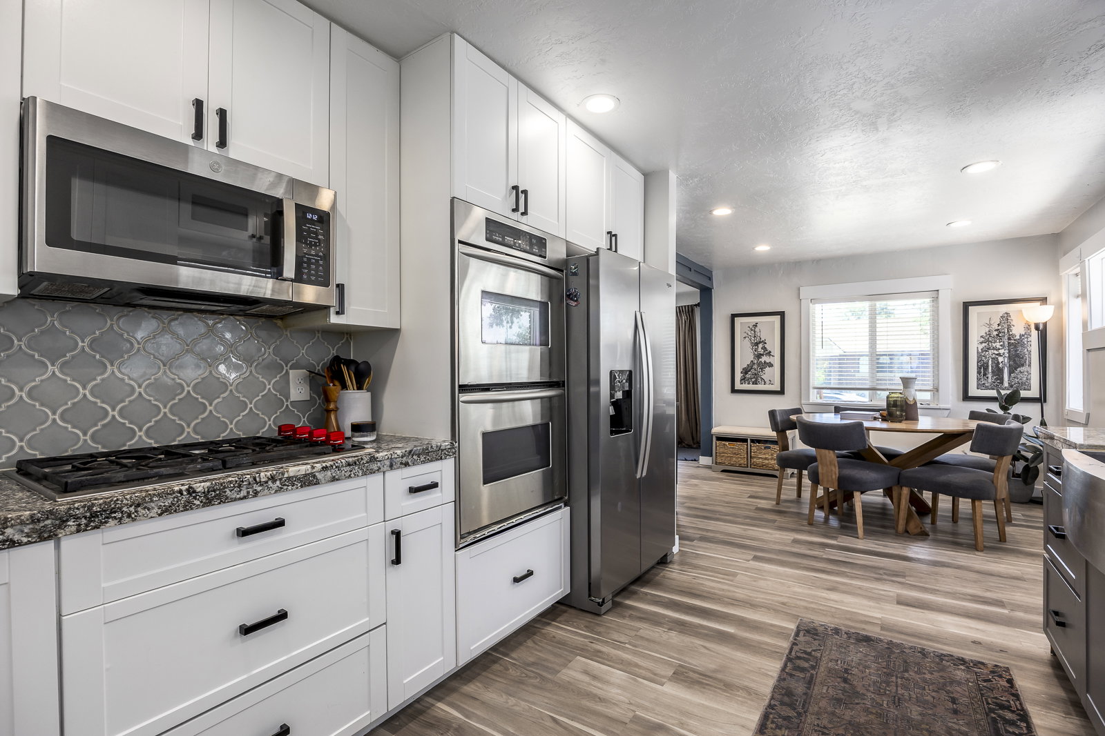 Modern kitchen featuring white cabinetry, stainless steel appliances, a tile backsplash, and stone countertops