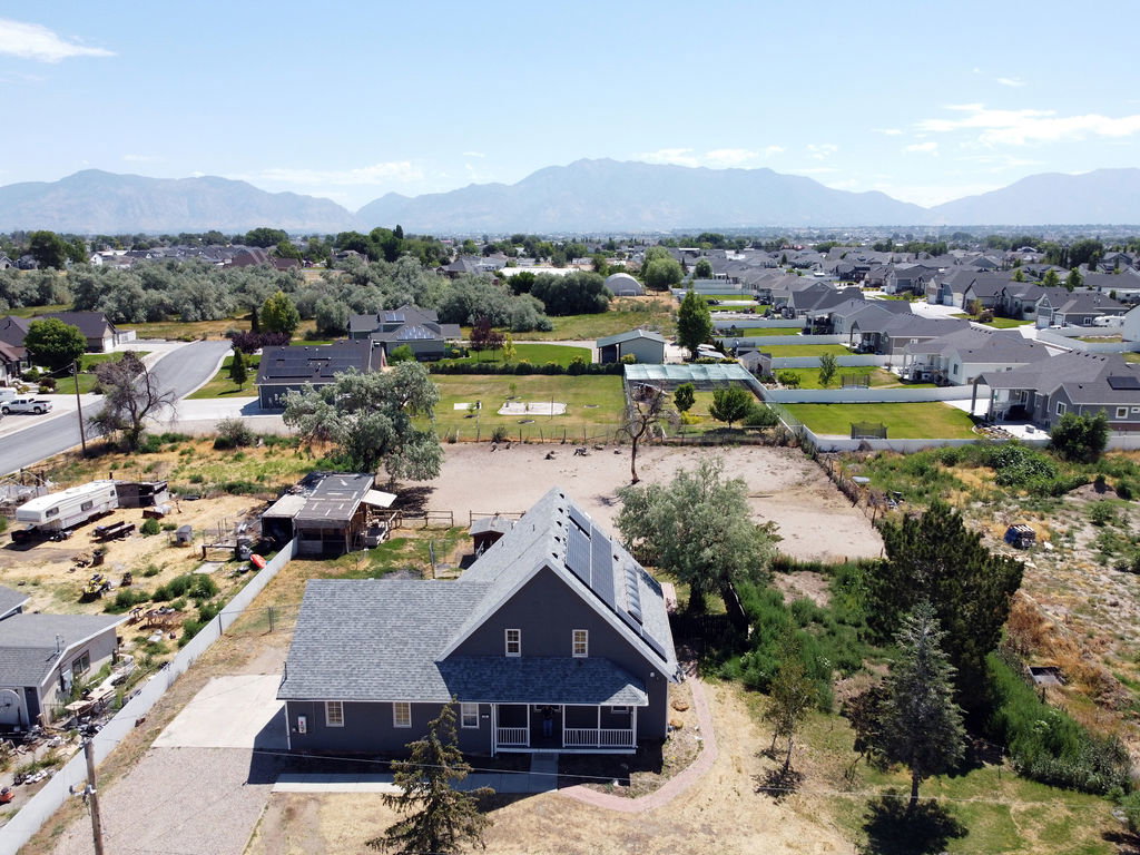 Gray exterior home featuring a covered front porch, a dark gray shingle roof, and roof-mounted solar panels