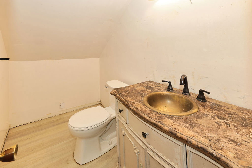Bathroom featuring a vanity with a patterned countertop, a bronze-toned basin, and dark-finished hardware