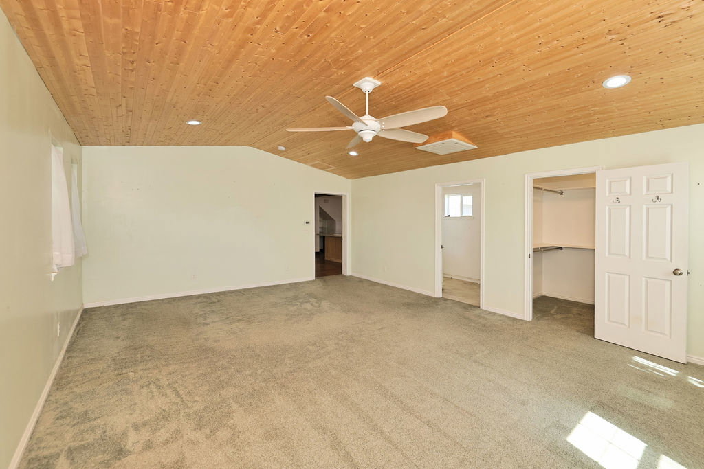 Sloped wood-paneled ceiling with recessed lighting and a ceiling fan