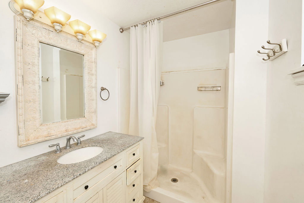 Bathroom featuring a white vanity with louvered doors, a speckled countertop, and an oval undermount sink