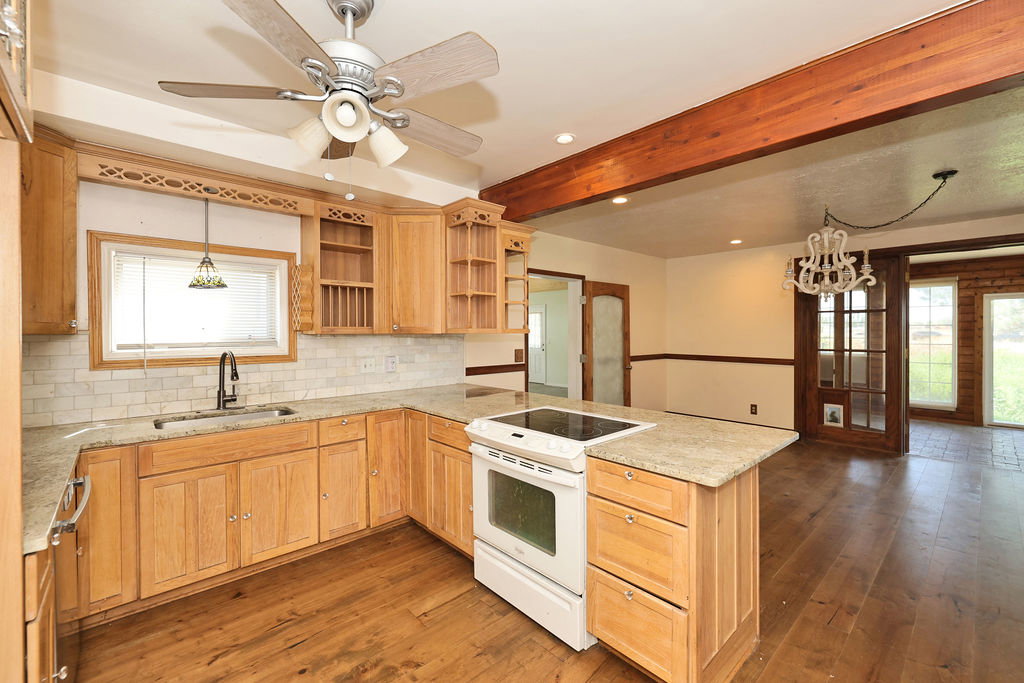 Kitchen featuring wood-finish flooring, light wood cabinetry, stone countertops, a white tile backsplash, and a built-in electric range