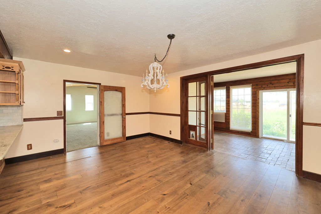 Wood-finish flooring throughout the main area, complemented by a decorative chandelier