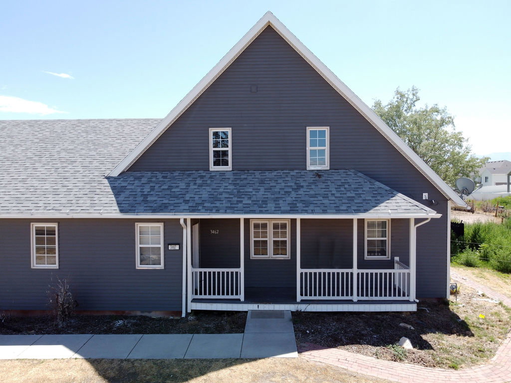 Gabled home exterior featuring gray siding and white trim