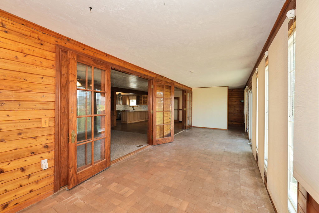Enclosed patio featuring brick-style flooring and wood-paneled walls