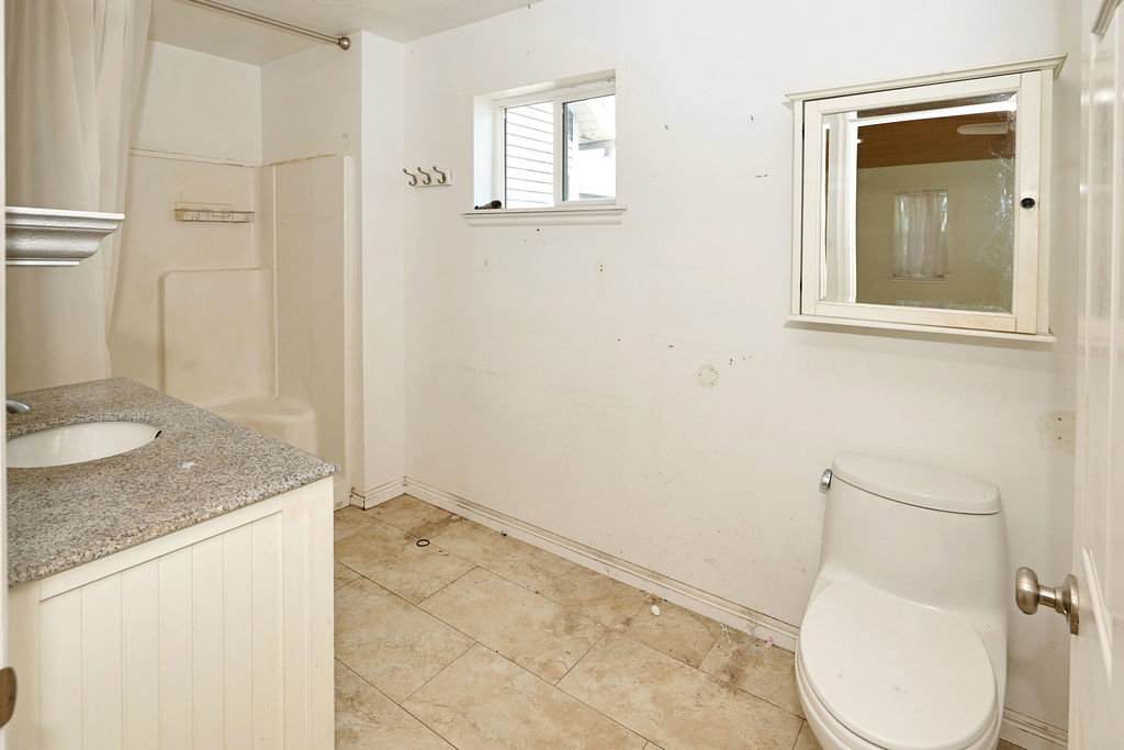 Bathroom featuring a built-in shower, single-sink vanity with a granite-style countertop and beadboard cabinetry, tile flooring, and a window for natural light