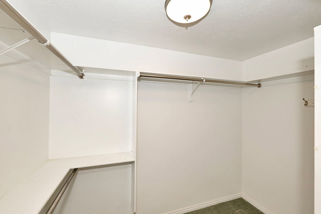 Walk-in closet with built-in shelving, multiple hanging rods, and a ceiling-mounted light fixture