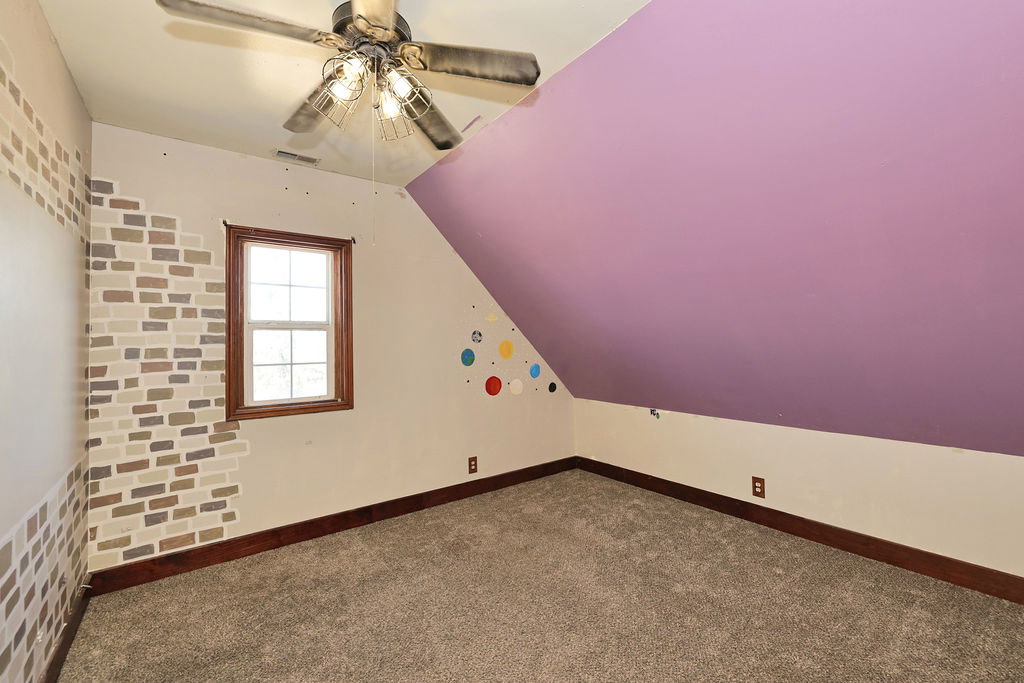 Carpeted room featuring an angled ceiling and a ceiling fan
