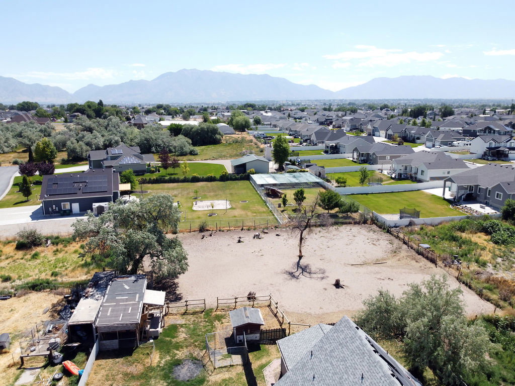 Expansive property featuring a large open lot, surrounding residential structures, and distant mountains