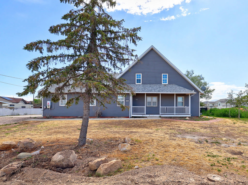 Gable-roofed home featuring gray siding, a covered front porch with white railing, and white-framed windows
