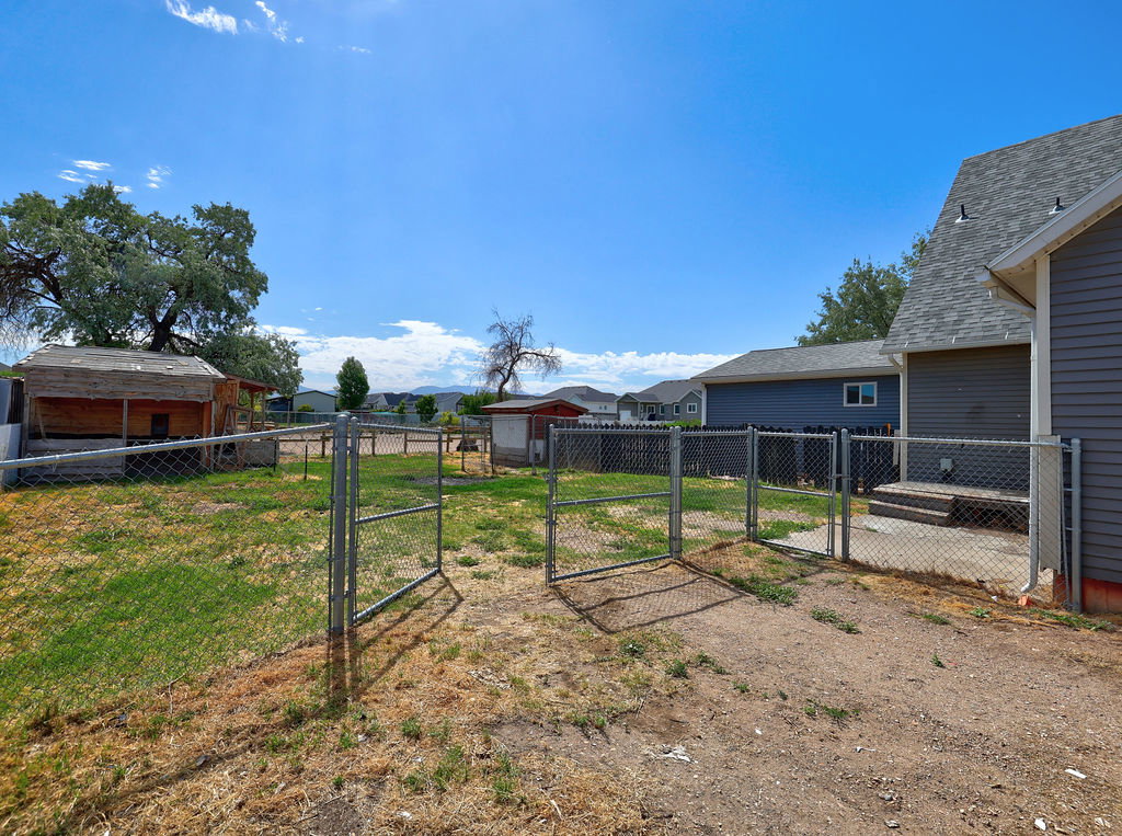 Expansive chain-link fenced backyard featuring a wooden shed and a mature tree