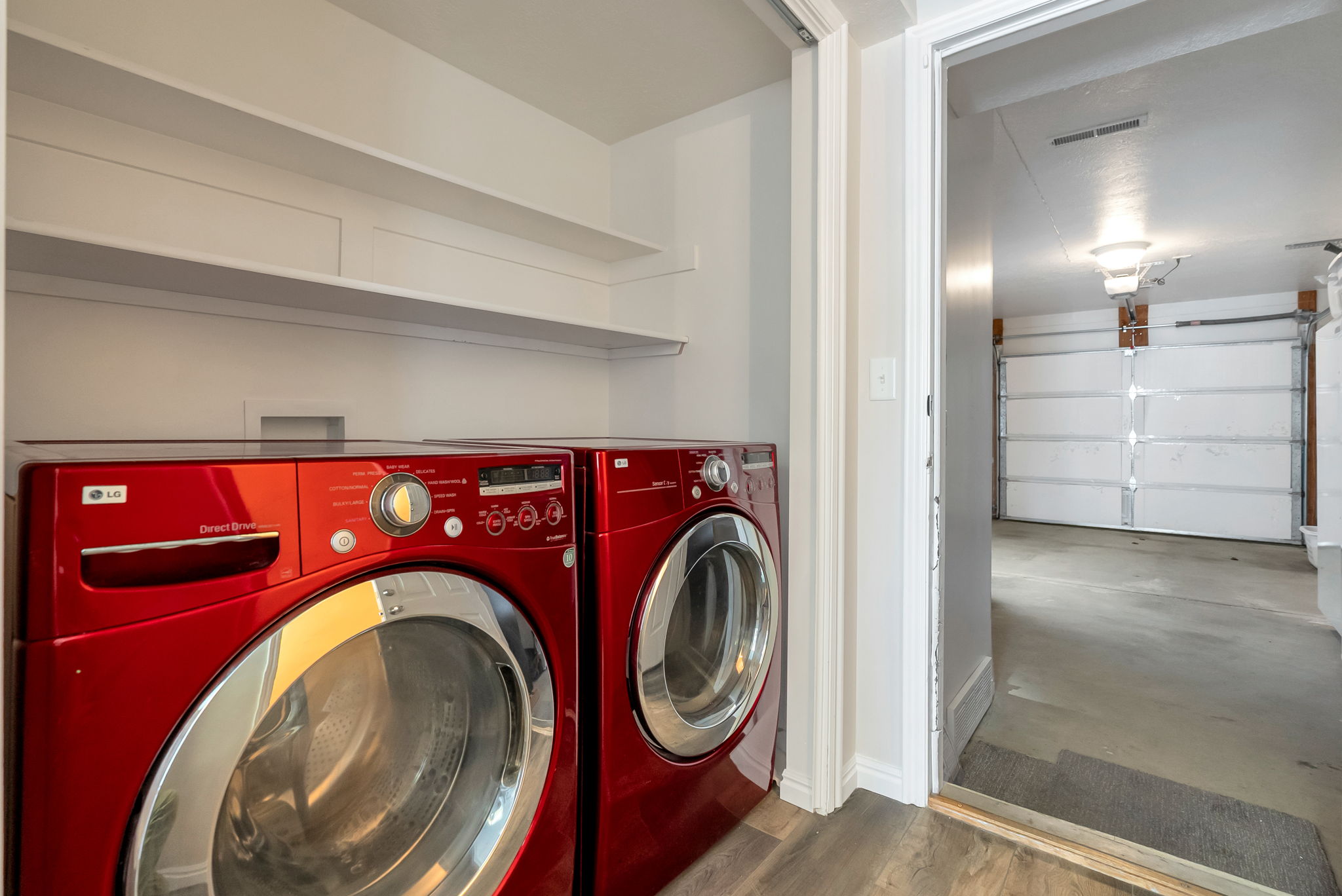 Dedicated laundry area featuring white shelving and wood-finish flooring