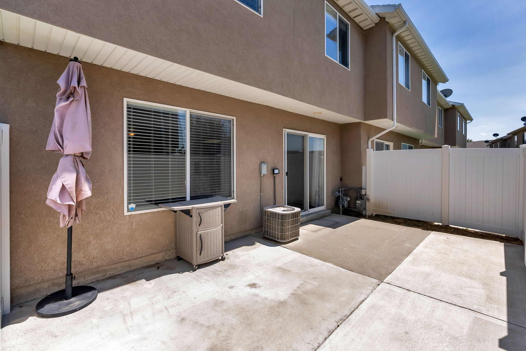 Private concrete patio area featuring a sliding glass door and a privacy fence