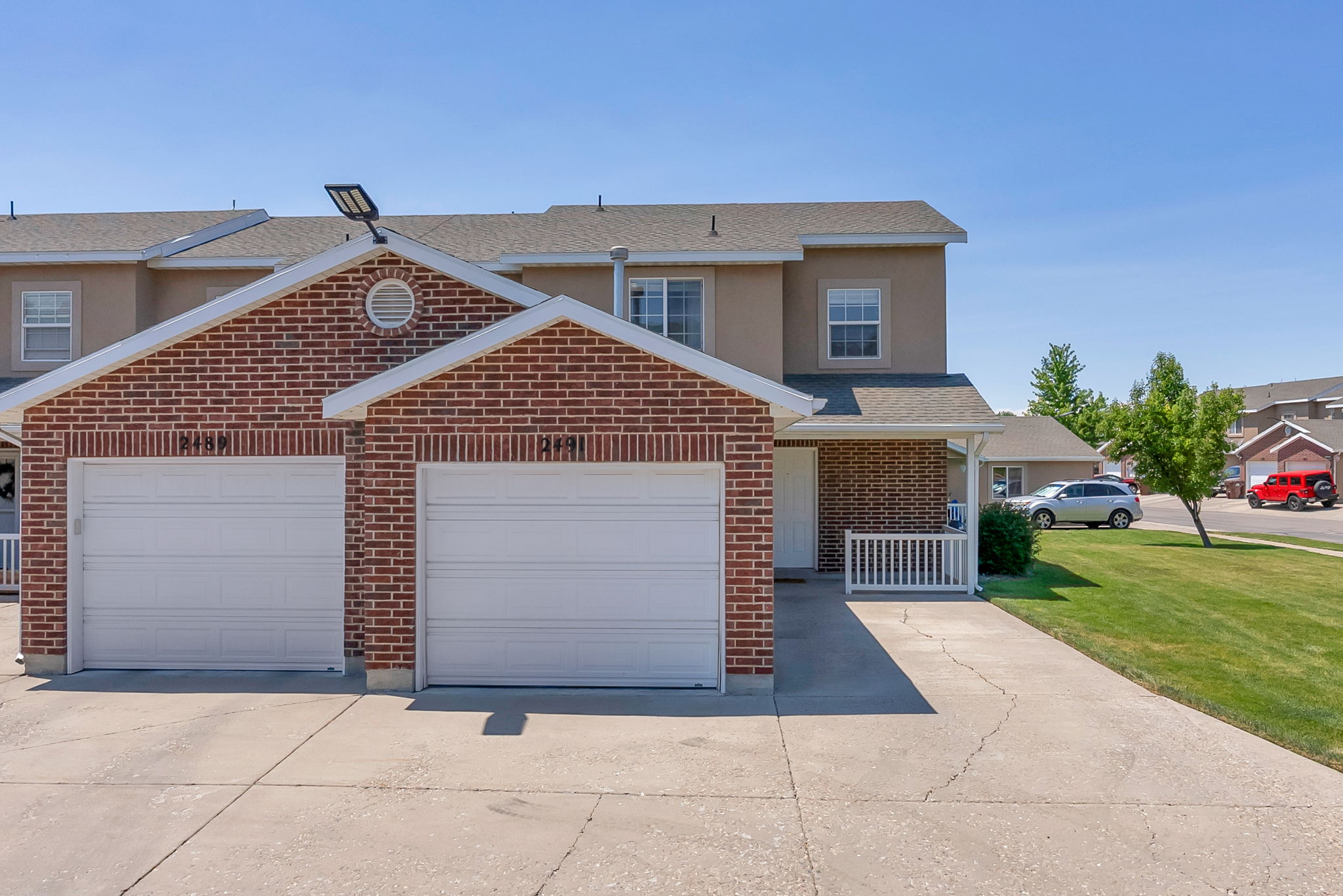 Brick facade townhome with a two-car garage and concrete driveway