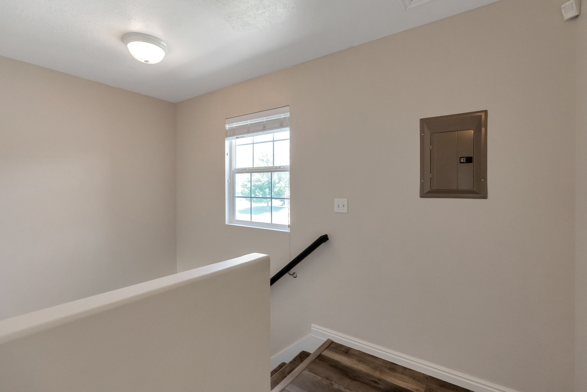Stairwell featuring light-toned wall paint, a double-hung window with blinds, and wood-finish flooring on the stairs