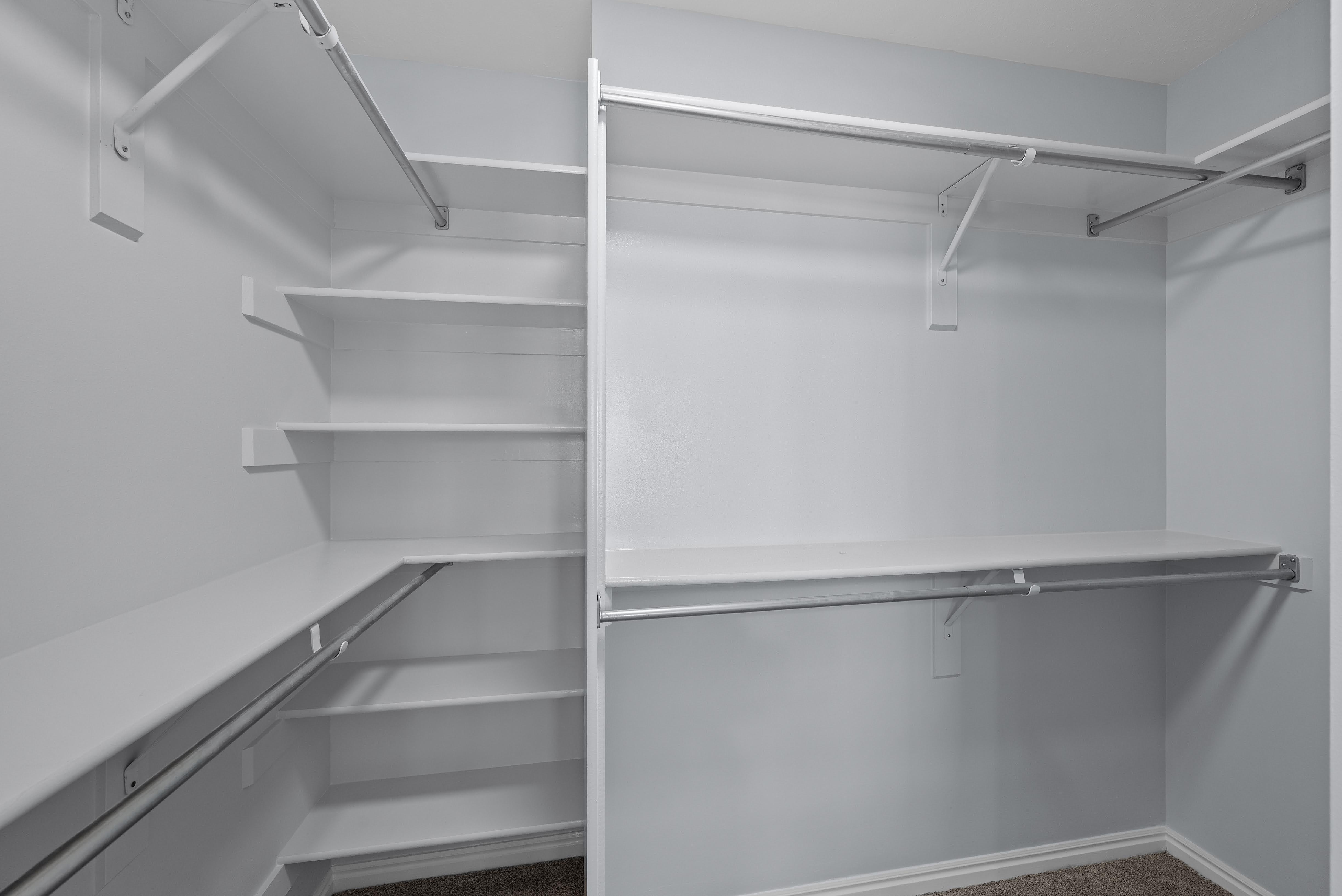 Built-in closet system featuring multiple white shelves and hanging rods