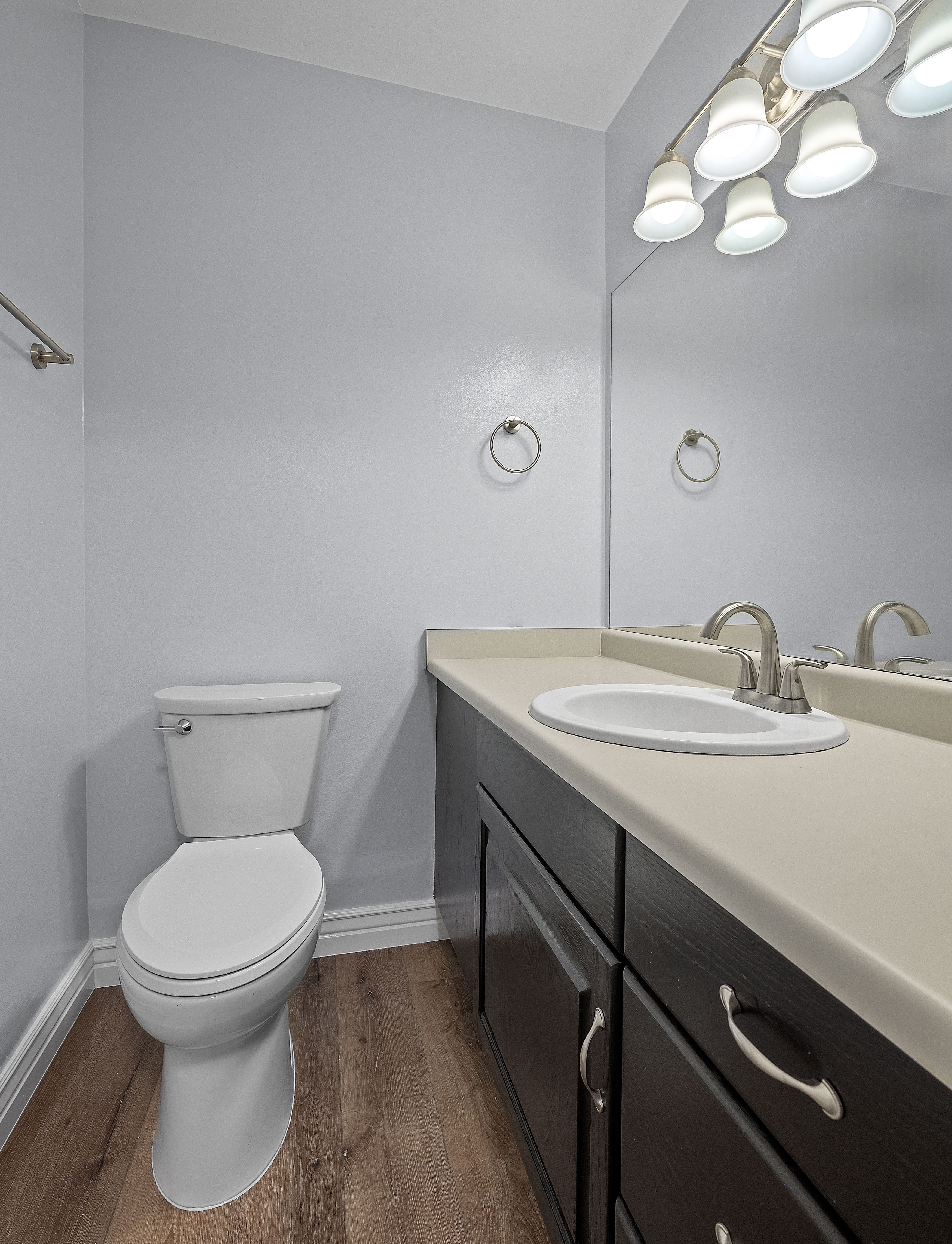 Bathroom vanity featuring a light-colored countertop with an integrated sink, dark wood-finish cabinetry, and brushed nickel hardware