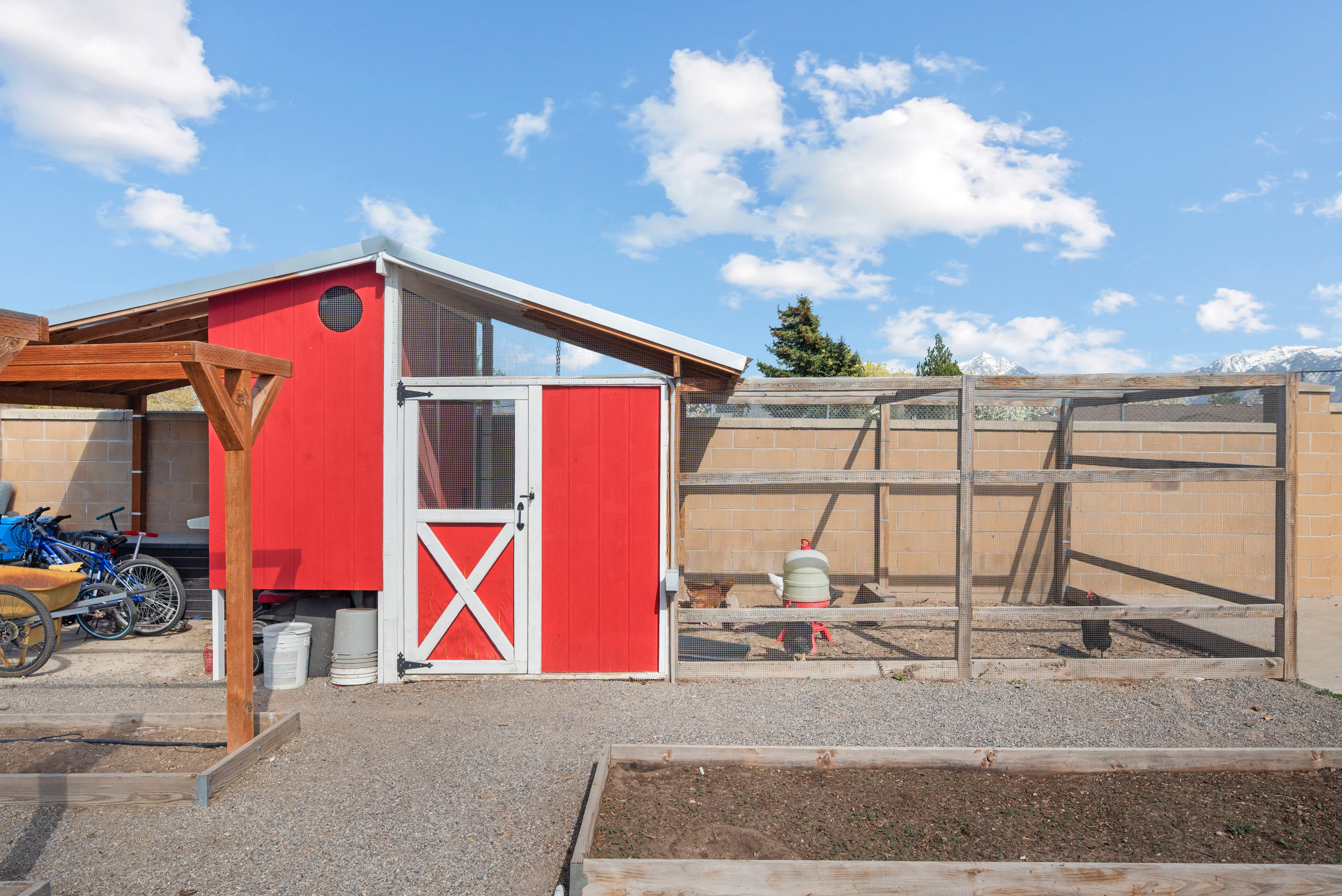Custom red outbuilding featuring a round window and a white Dutch door