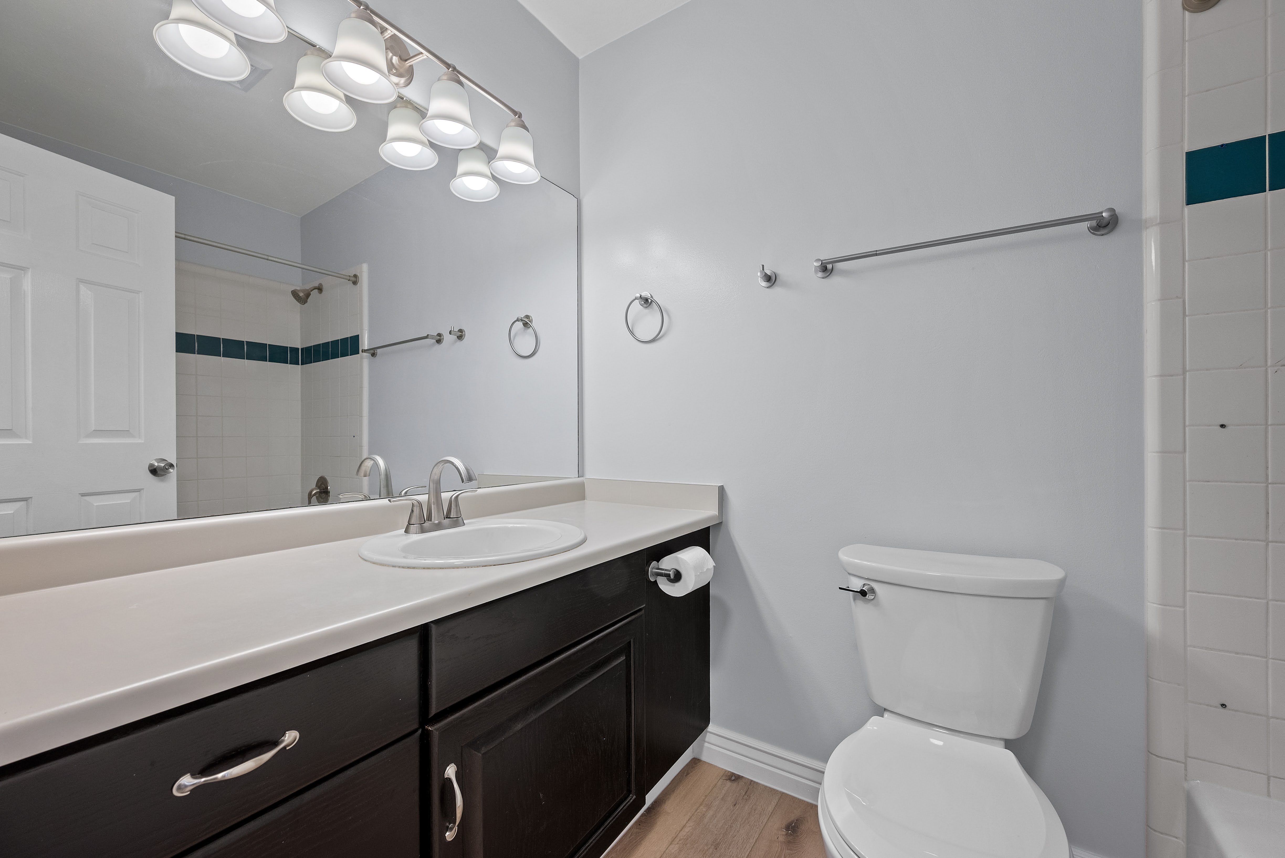 Bathroom featuring a single vanity with dark wood-finish cabinetry, a light-toned countertop, and an integrated oval sink with a chrome faucet