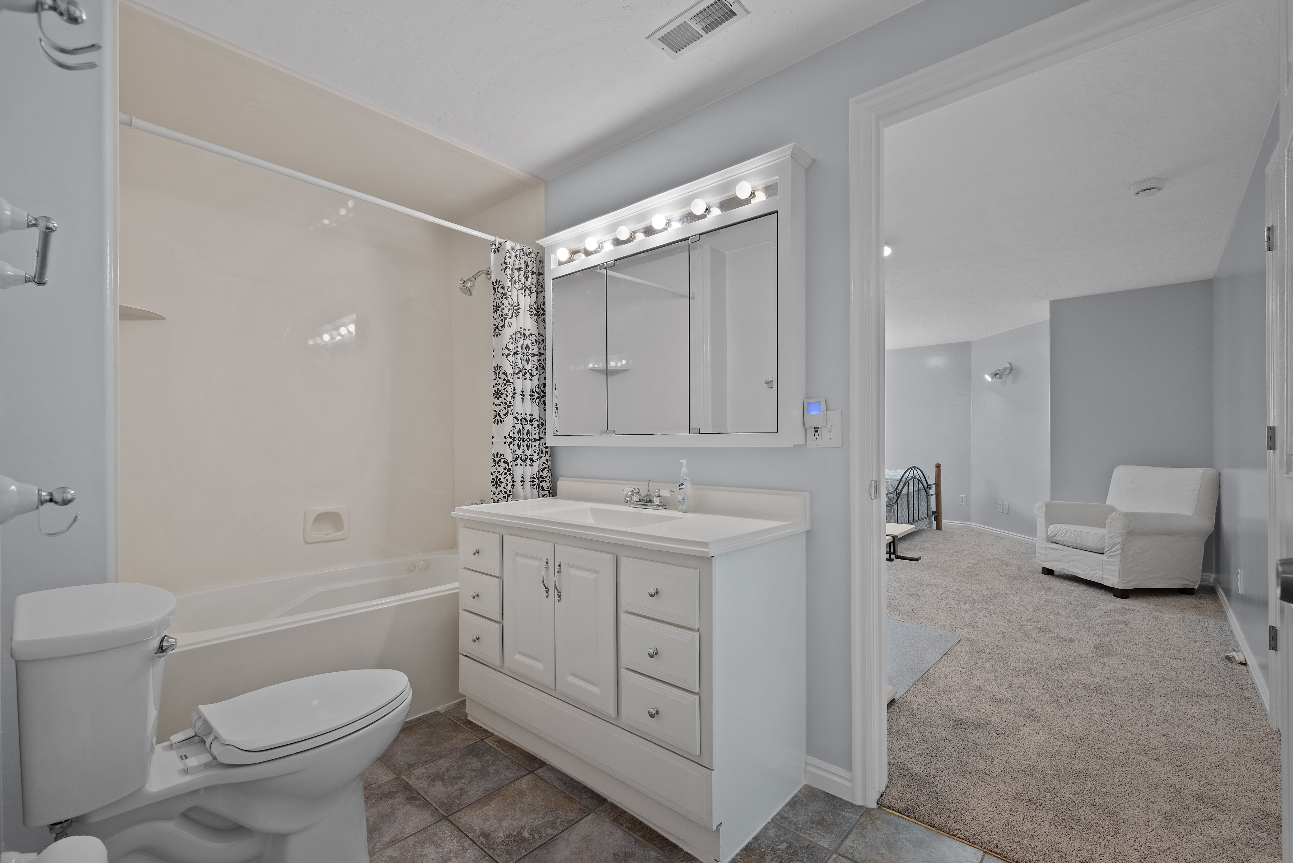 Full bathroom featuring a white vanity with integrated sink, overhead lighting fixture, and a combination shower/tub