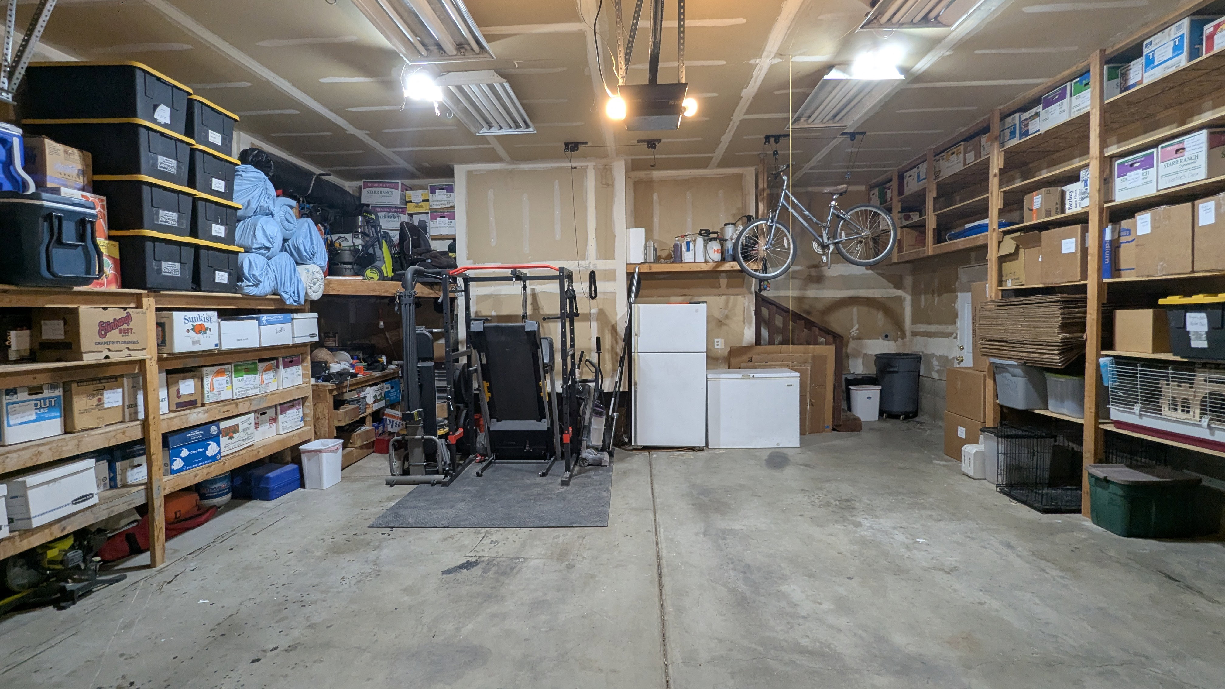 Spacious garage with concrete flooring, exposed ceiling joists, and extensive built-in shelving units