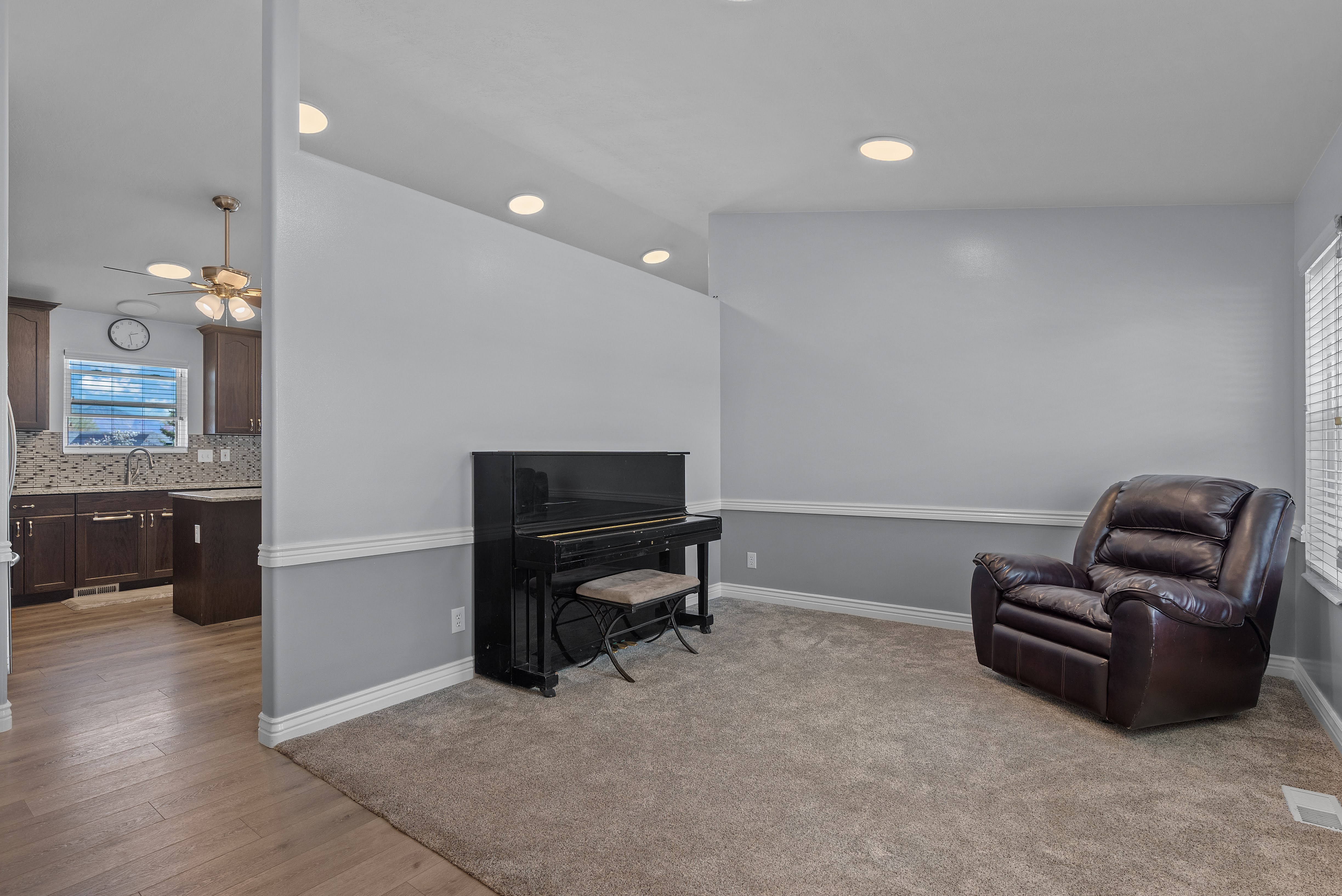 Carpeted living area featuring recessed lighting, a chair rail, and vertical blinds on the window