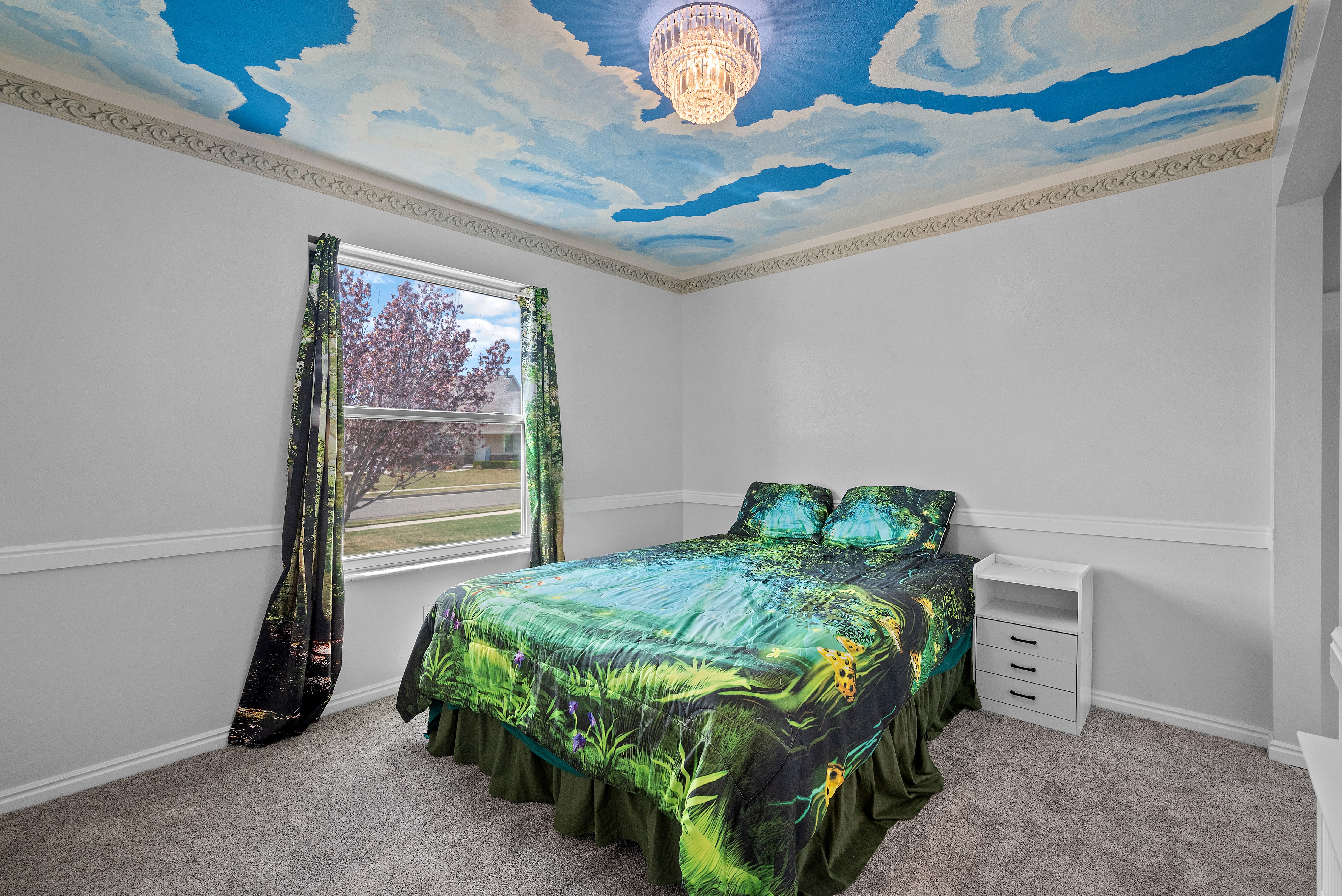 Ceiling mural featuring blue skies and clouds, complemented by a crystal chandelier