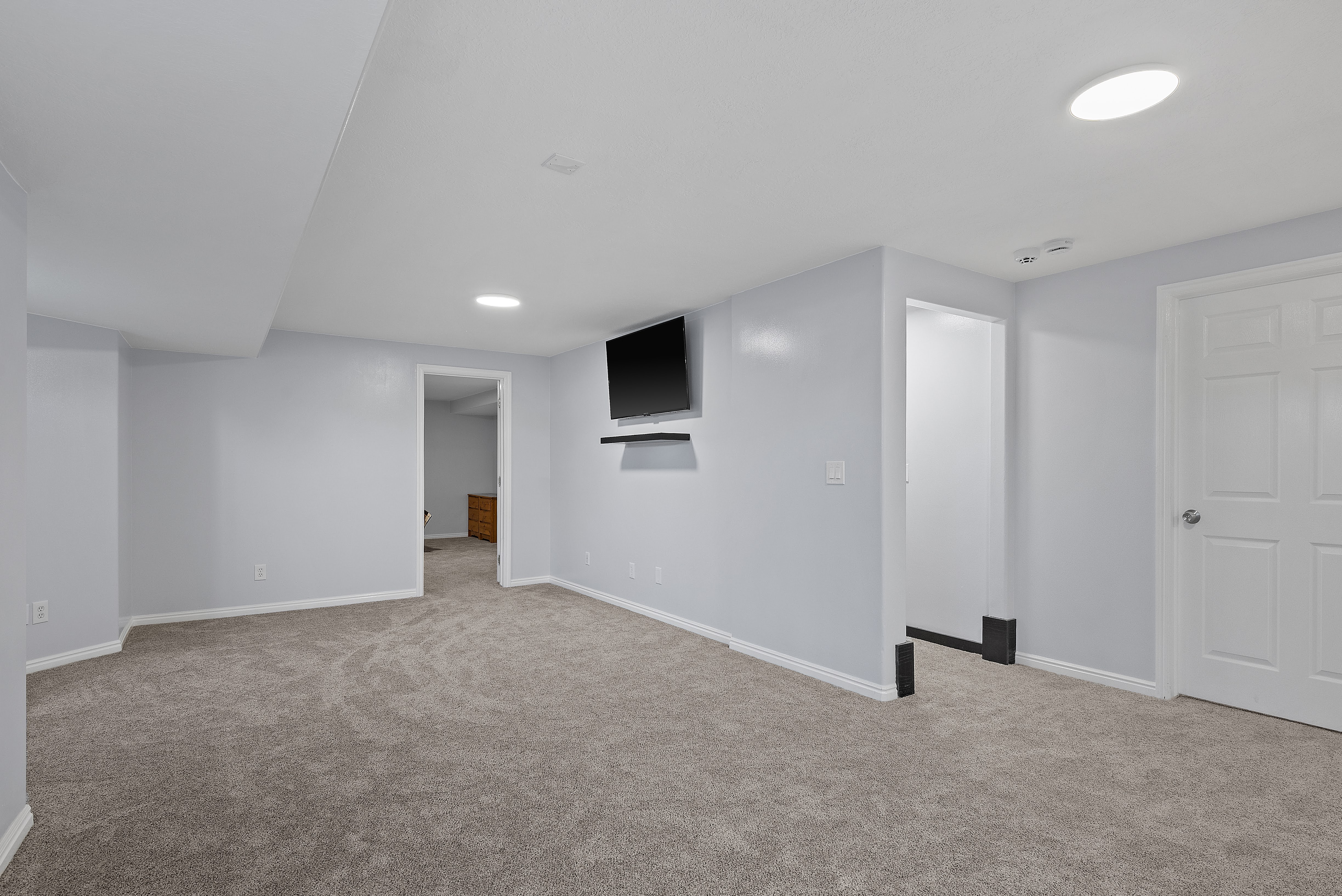 Spacious room featuring light gray wall paint, gray carpeting, recessed ceiling lighting, and white trim