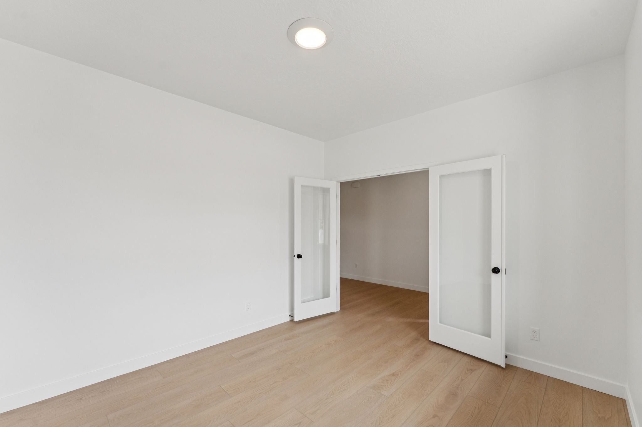 Main floor office featuring light wood-finish flooring, recessed ceiling lighting, crisp white walls, and white baseboards