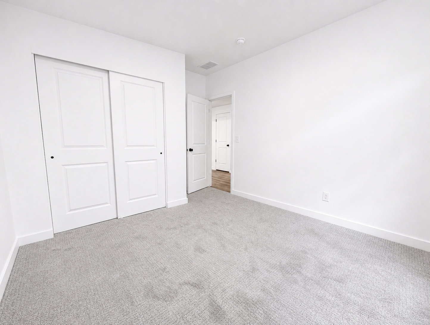 Basement bedroom featuring light gray carpeting, white walls, and white baseboards