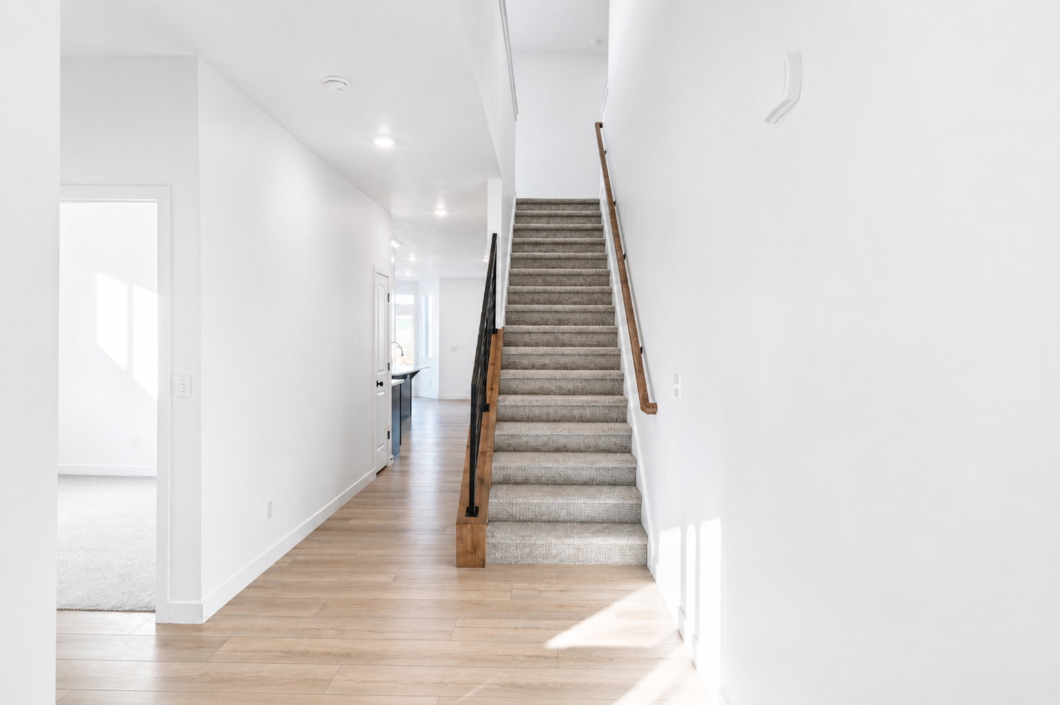 Entryway featuring wood-finish flooring and a staircase with a black metal and wood-finish railing