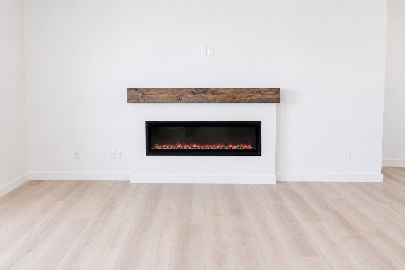 Linear electric fireplace with a wood-finish mantel and a light-toned wood-finish flooring