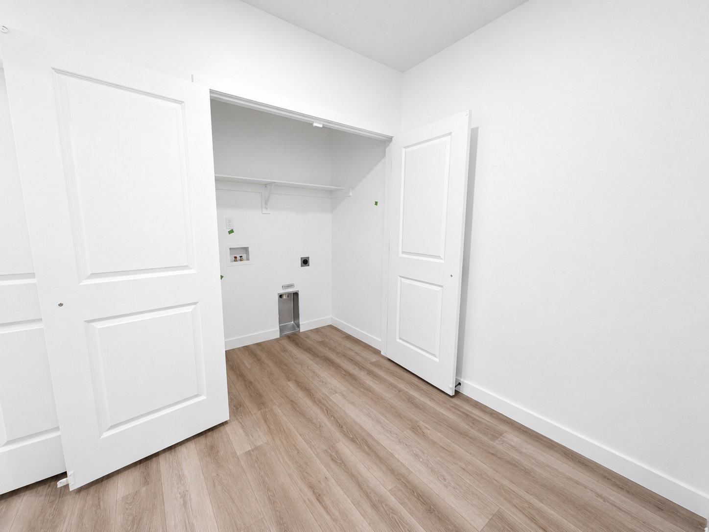 Basement ADU laundry area featuring wood-finish flooring and wood built-ins
