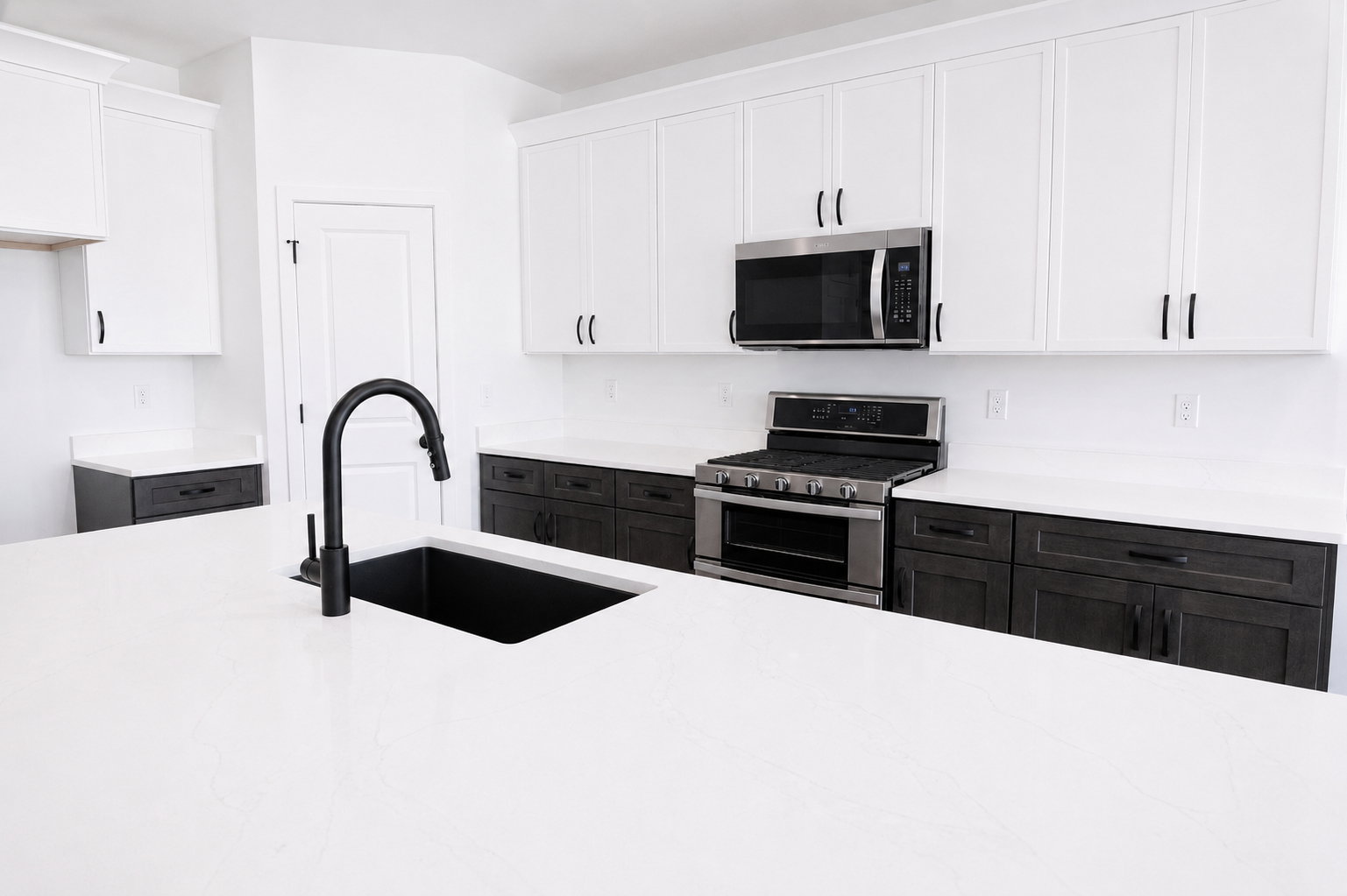 Spacious kitchen featuring a large island with an undermount sink and matte black faucet, two-tone cabinetry, stainless steel appliances, and extensive counter space