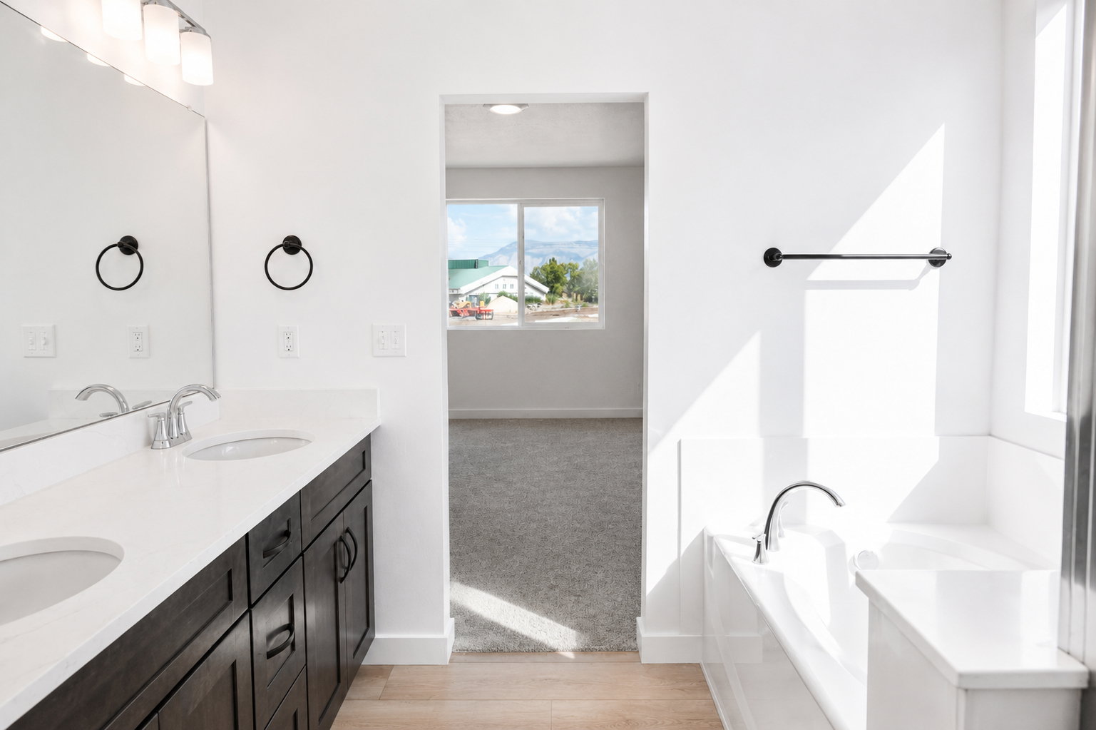 Primary bathroom featuring a double vanity with dark wood cabinetry, quartz countertops, and a separate tub and shower