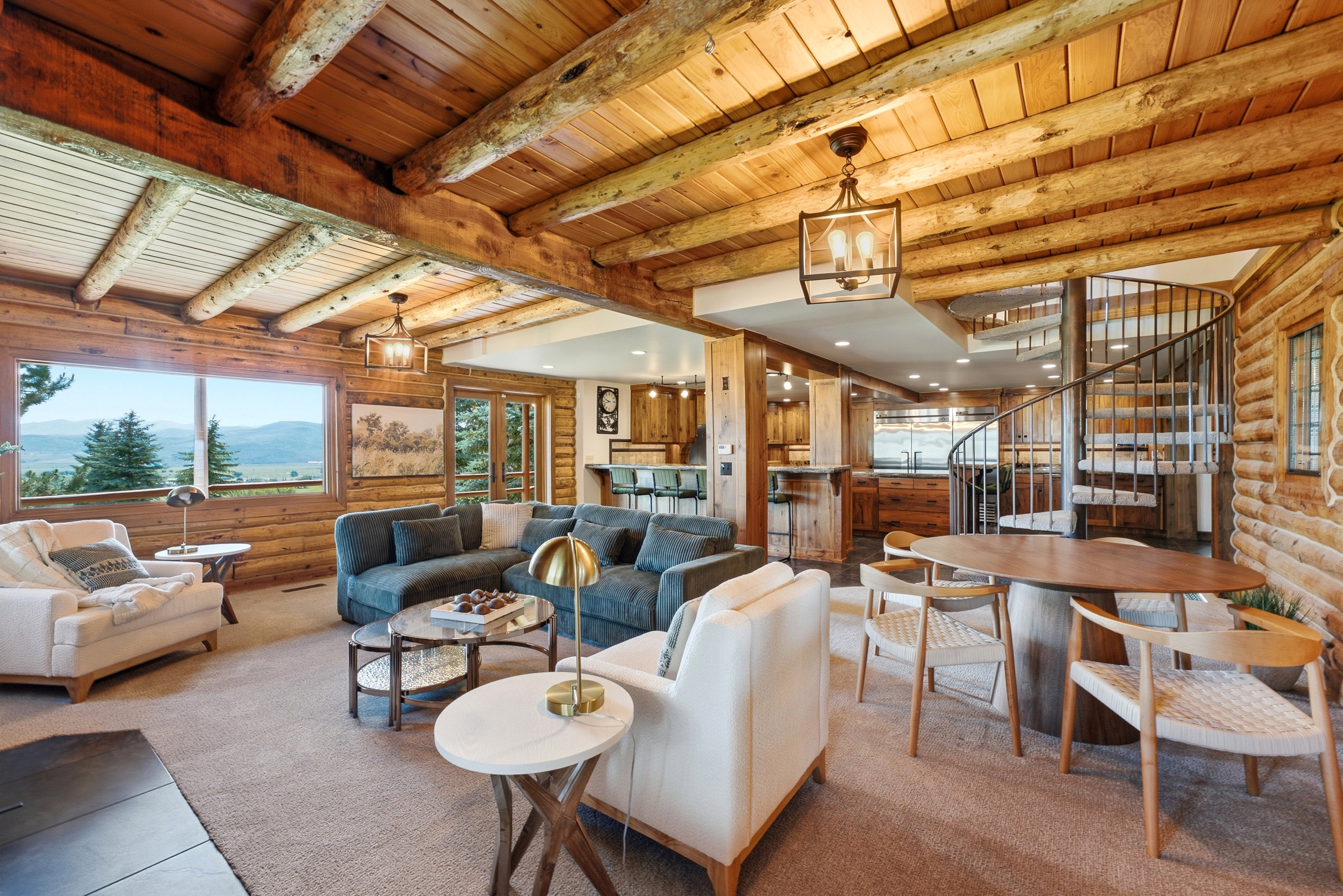 Expansive open-concept living space featuring log walls and exposed beam ceilings
