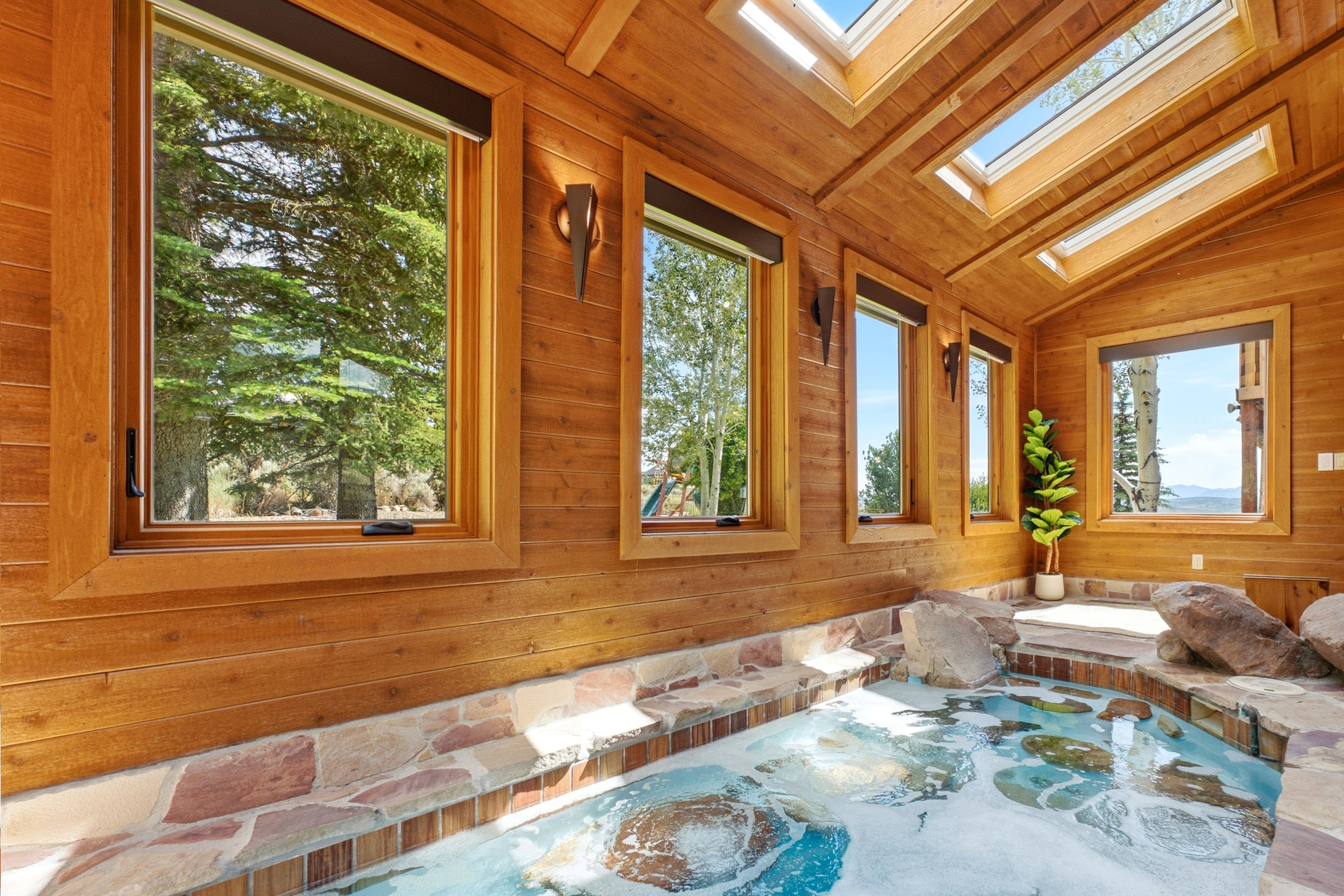 Indoor spa featuring a stone surround, integrated natural rock elements, and a wood-paneled ceiling