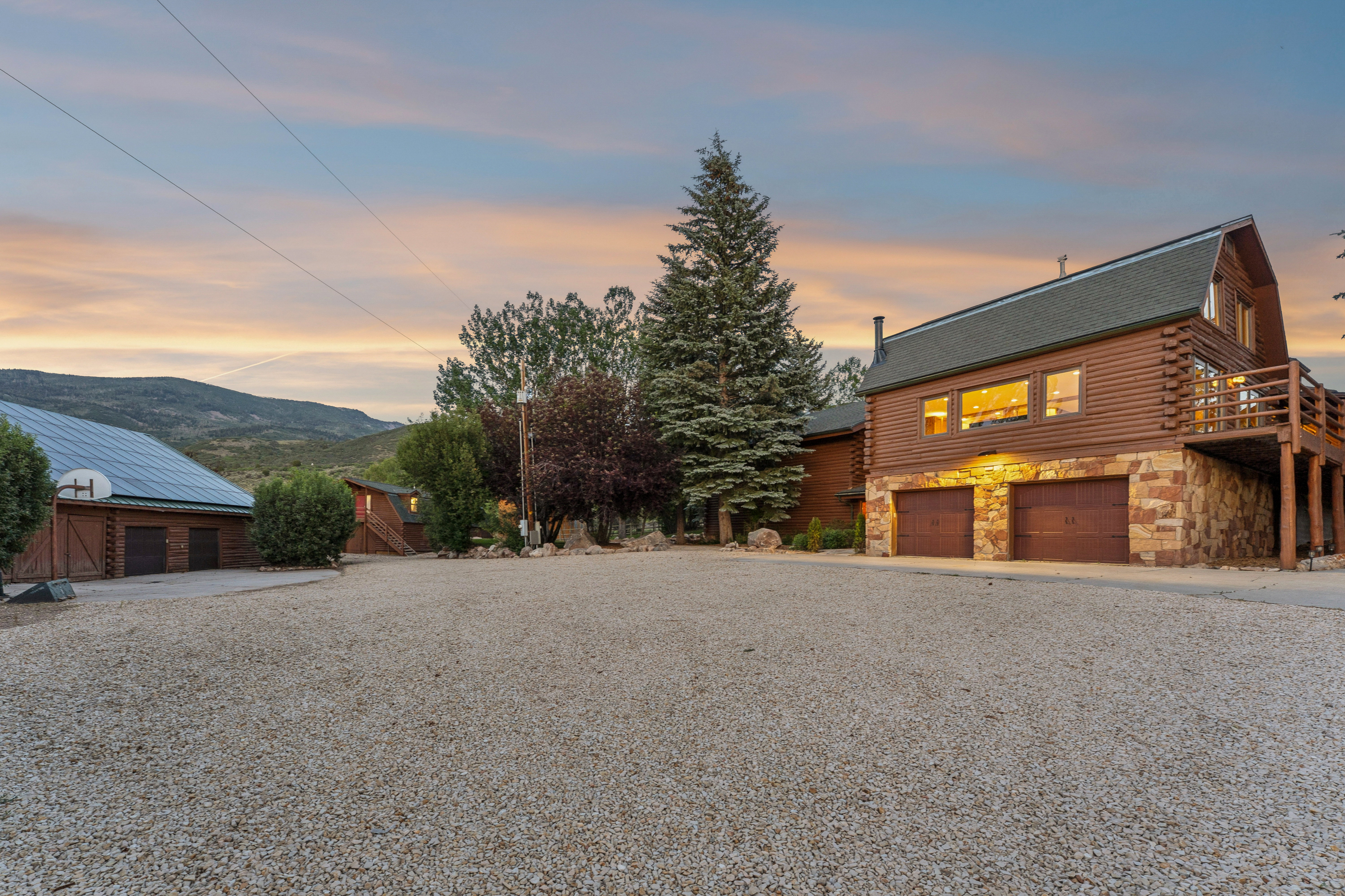 Log-sided residence featuring a multi-story design with stone accents and a two-car garage
