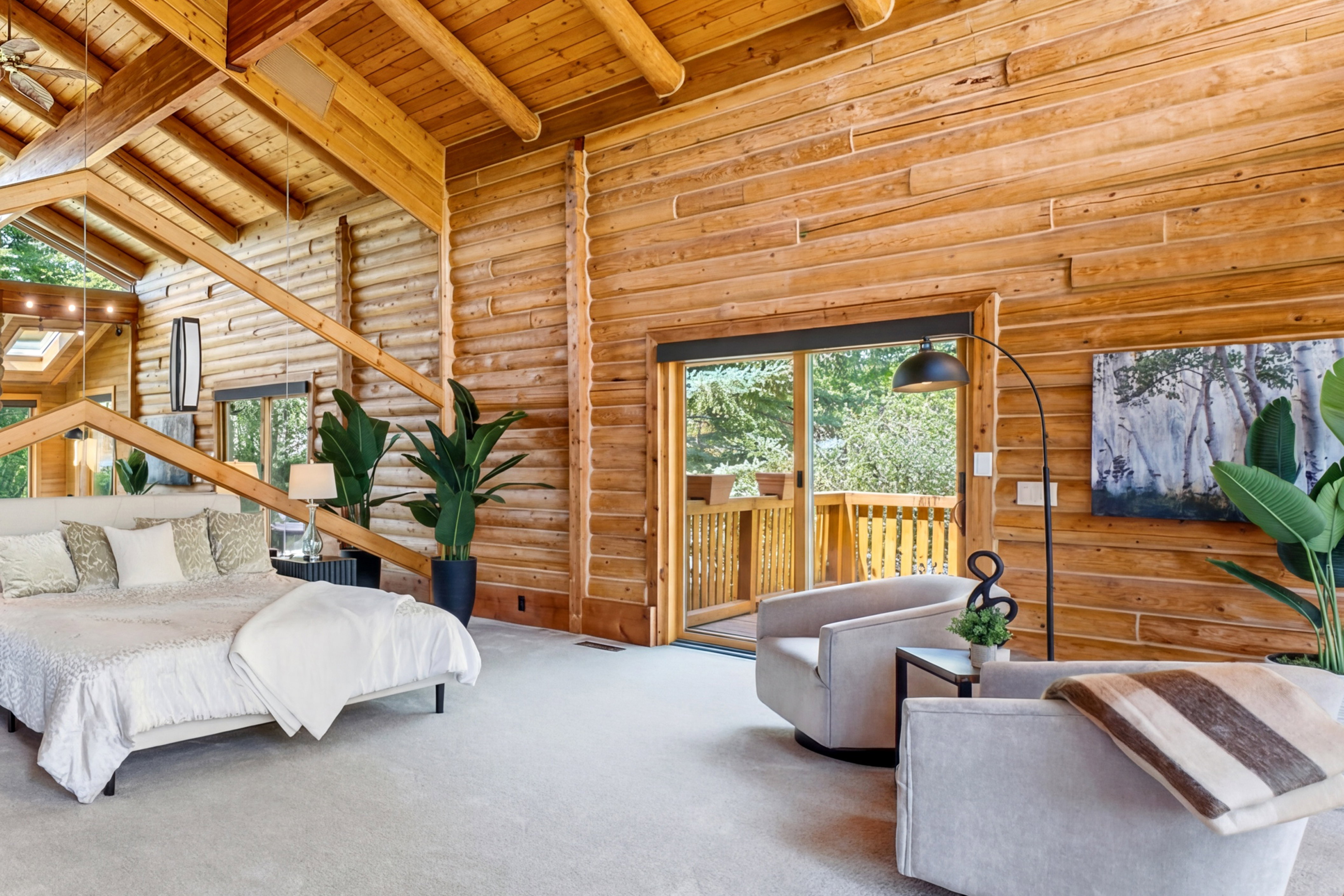 Expansive room featuring natural log walls, a vaulted wood-beam ceiling with exposed rafters, and light-toned carpeting