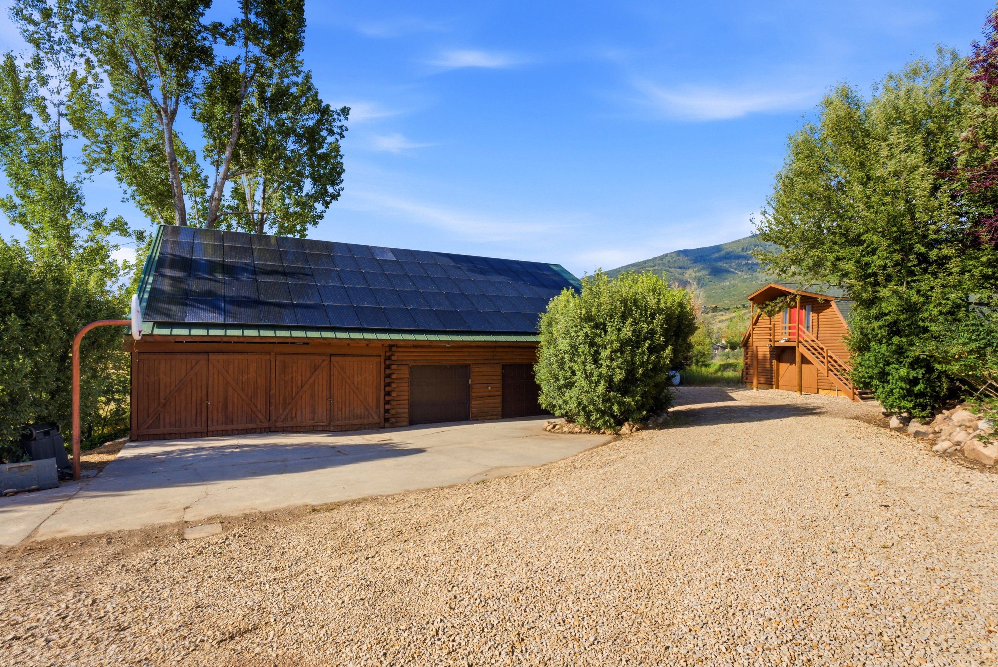 Expansive gravel drive with concrete approach leading to a multi-bay garage structure