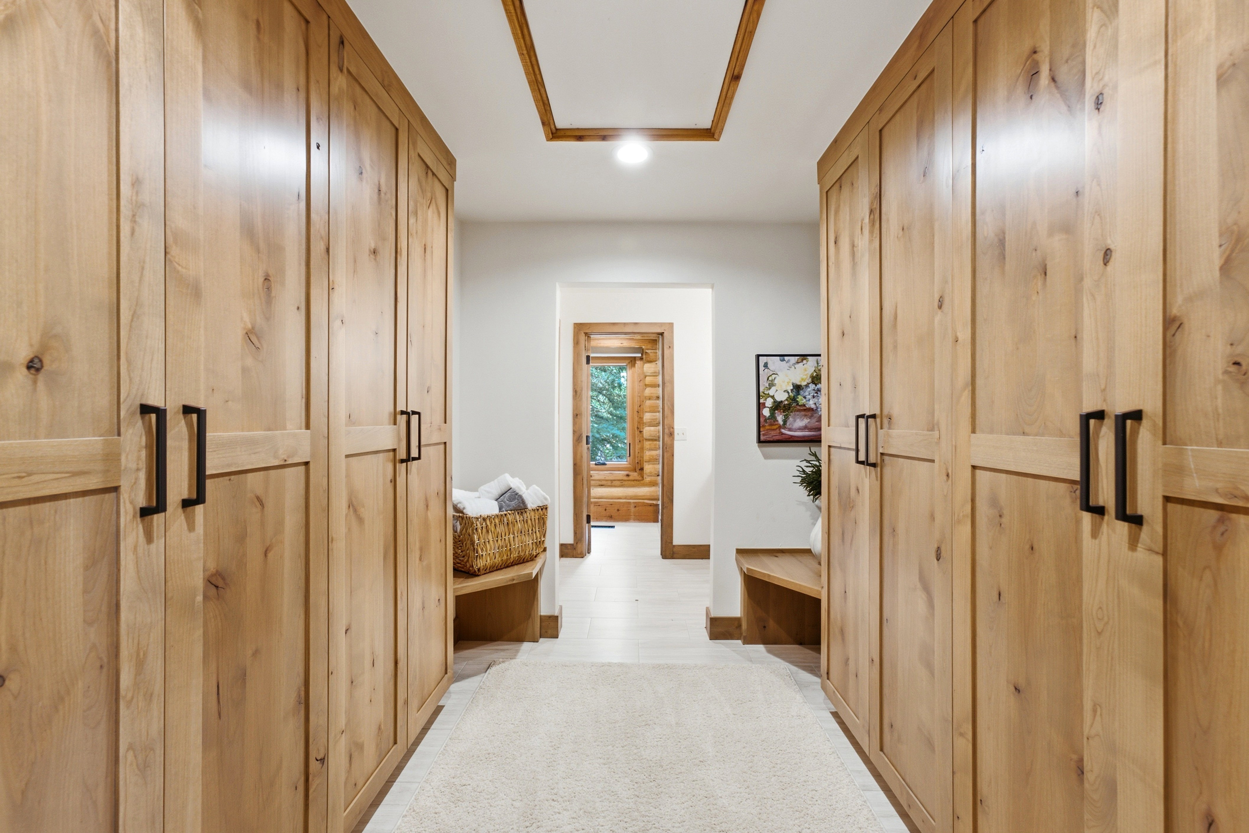 Hallway featuring extensive built-in wooden cabinetry with black hardware, recessed lighting, and a tray ceiling with wood trim