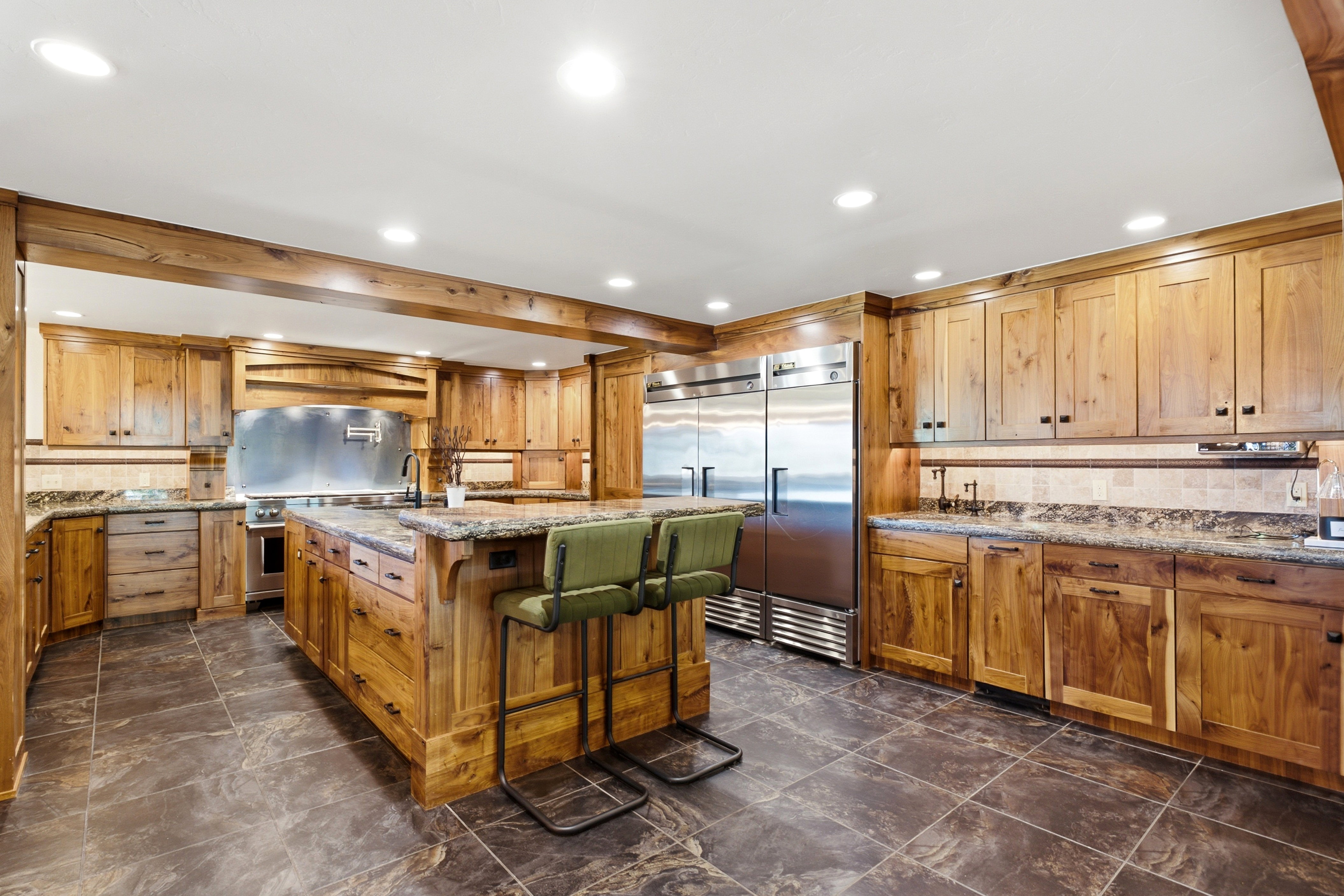 Spacious kitchen featuring extensive wood cabinetry, granite-finish countertops, and a large central island with seating