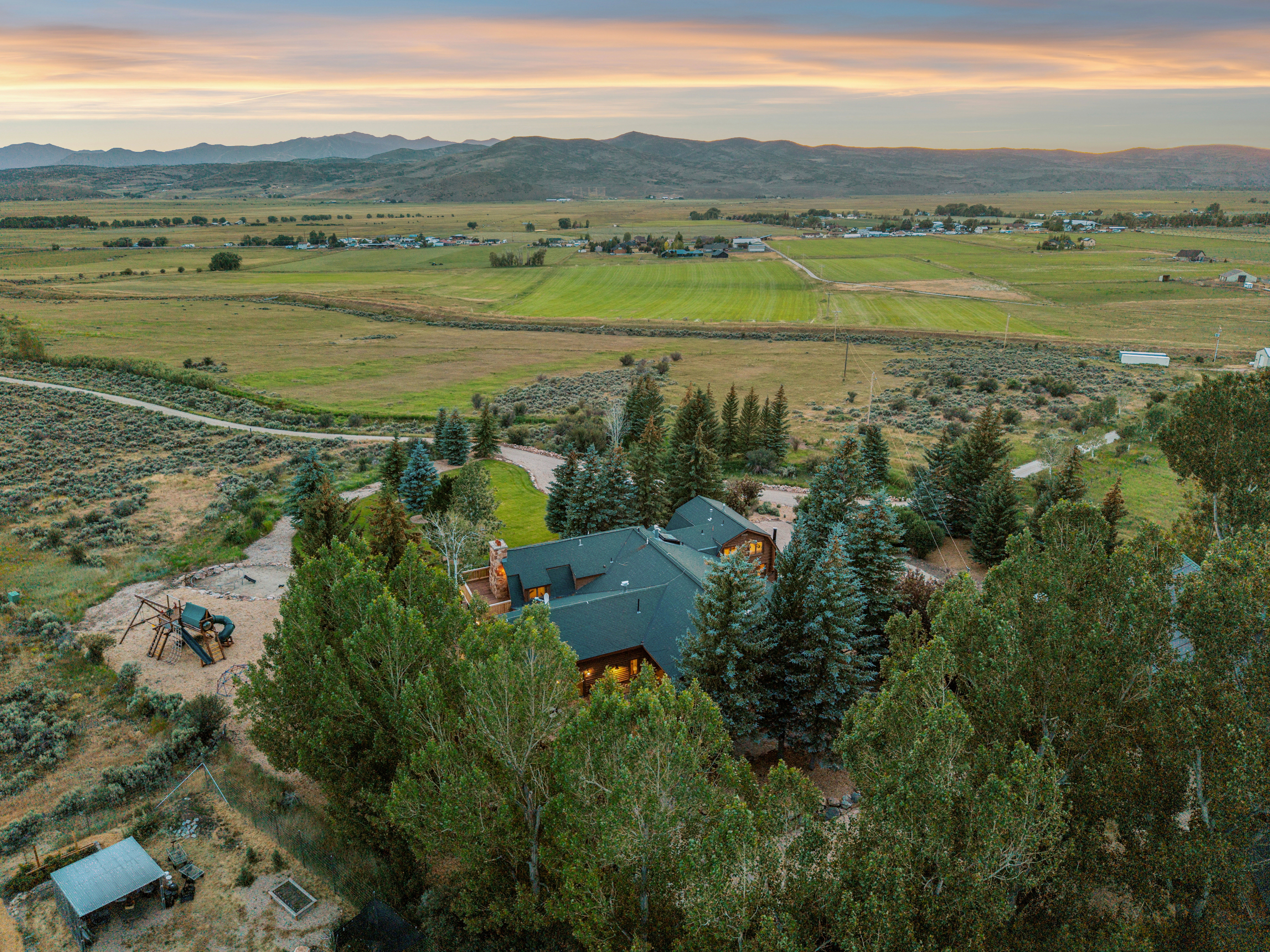Mountain backdrop with expansive green fields and distant structures