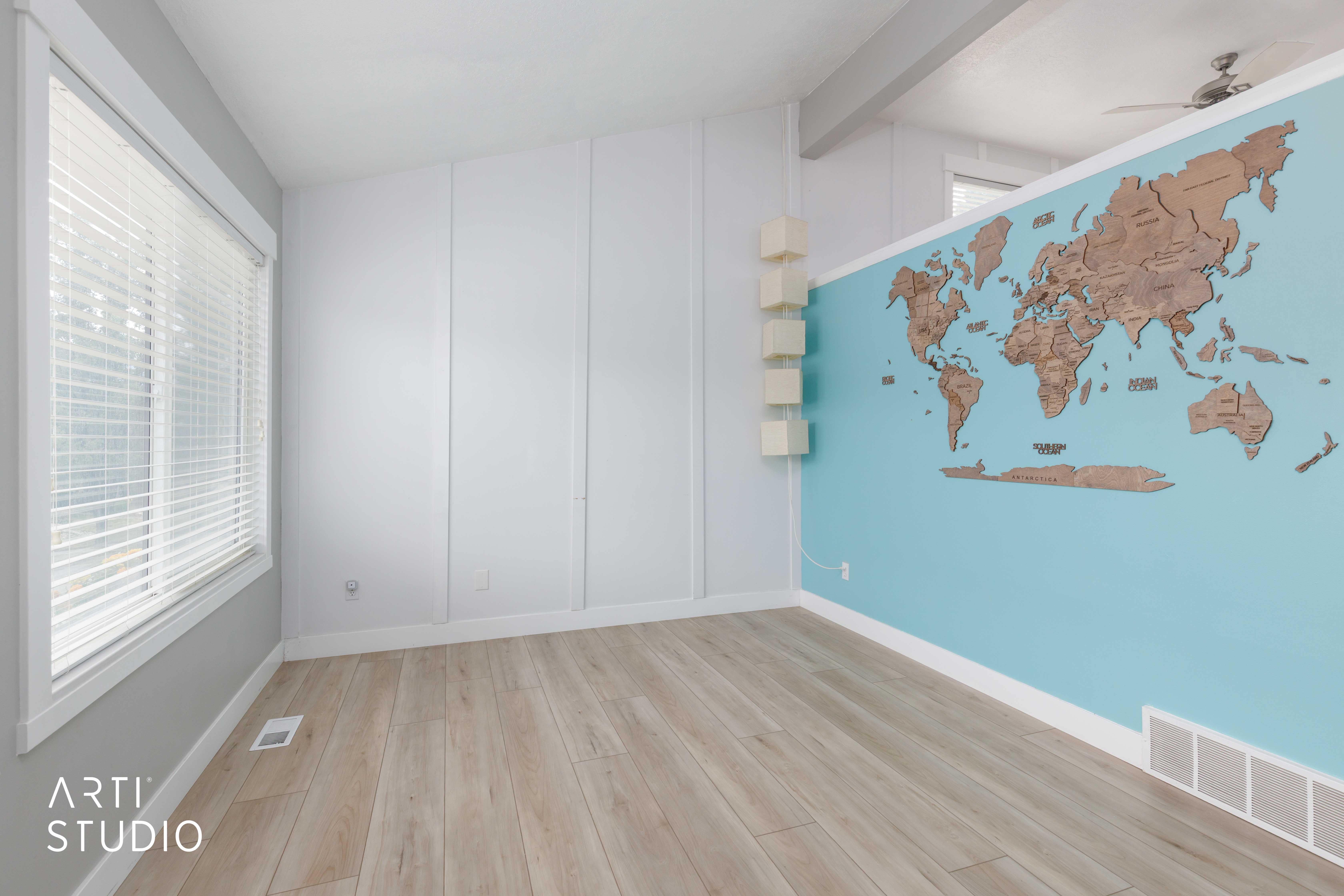 Bright interior space featuring wood-finish flooring, a large window with blinds, and white baseboards